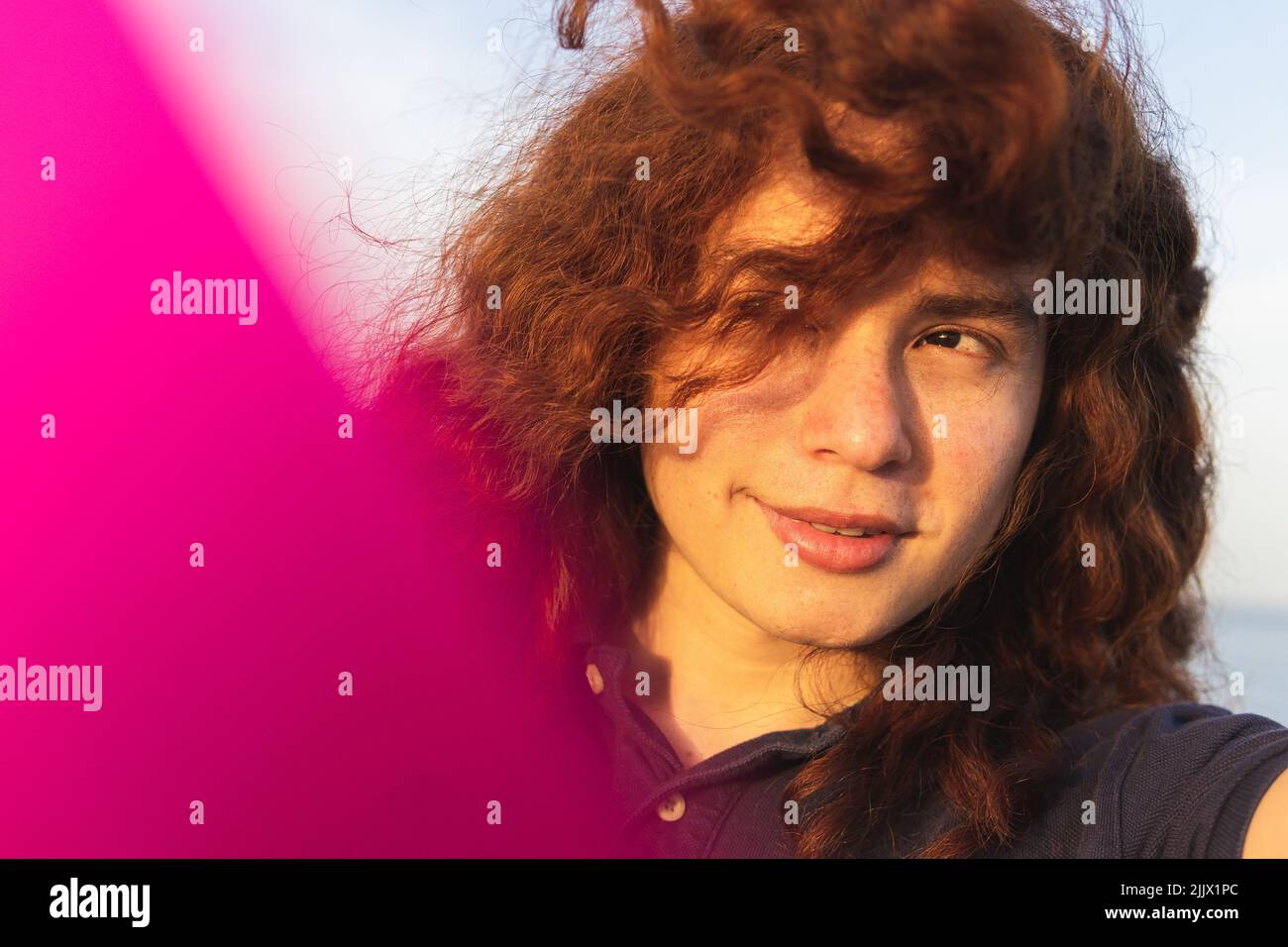 Primo piano della giovane Donna con i capelli tousled che guardano via durante il giorno di sole Foto Stock