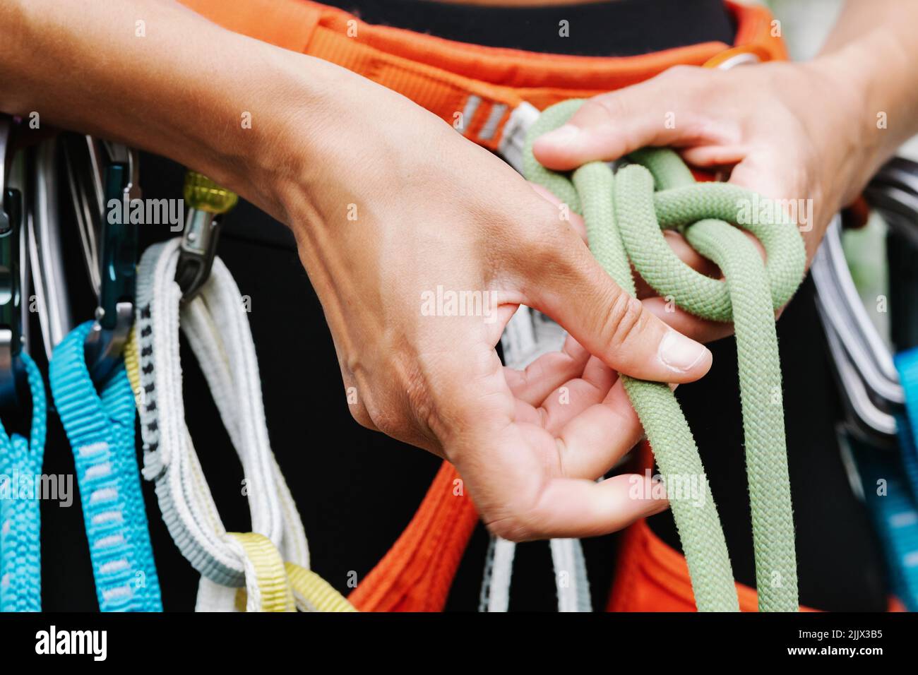 Sezione centrale dell'imbracatura della fune di legatura dell'escursionista femminile mentre si prepara per il rappelling Foto Stock