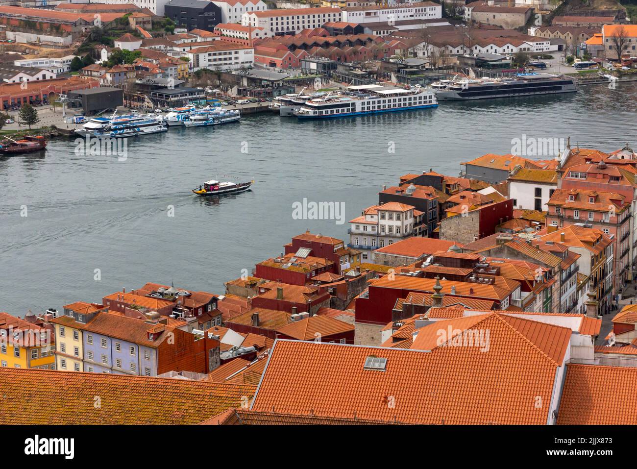 Vista sui tetti verso gli edifici nel centro di Porto, una delle principali città del Portogallo settentrionale con il fiume Douro in lontananza. Foto Stock