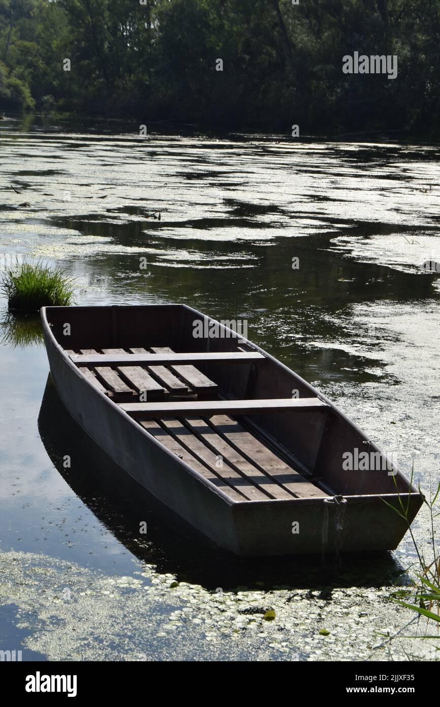 Barca in legno a fondo piatto sul fiume Klátovská Rameno nell'isola di Rye in formato verticale Foto Stock