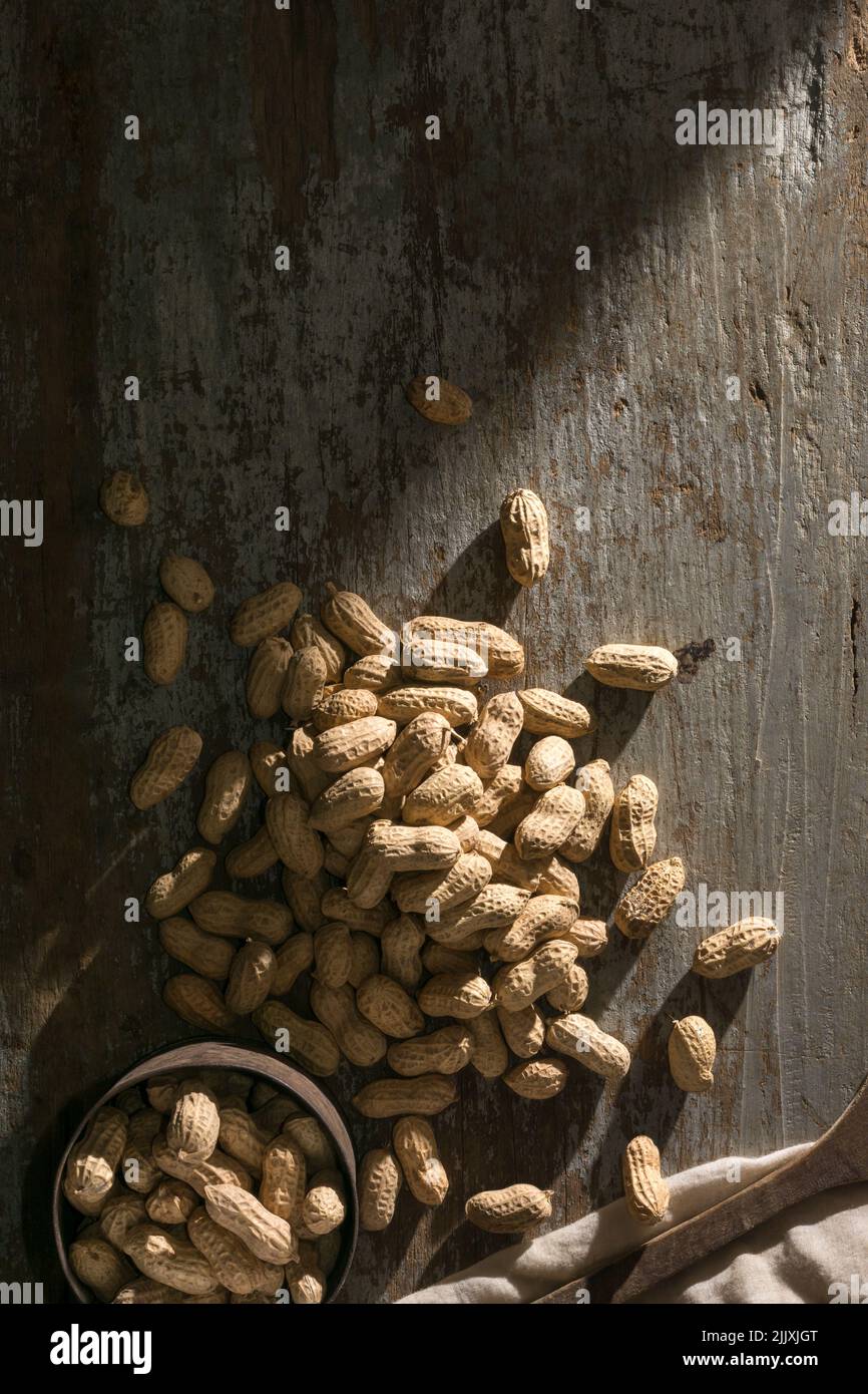 mucchio di arachidi non pelate su un fondo di legno con vecchia tazza, anche conosciuta come arachidi, goober, pindar o dado della scimmia, preso direttamente dall'alto Foto Stock