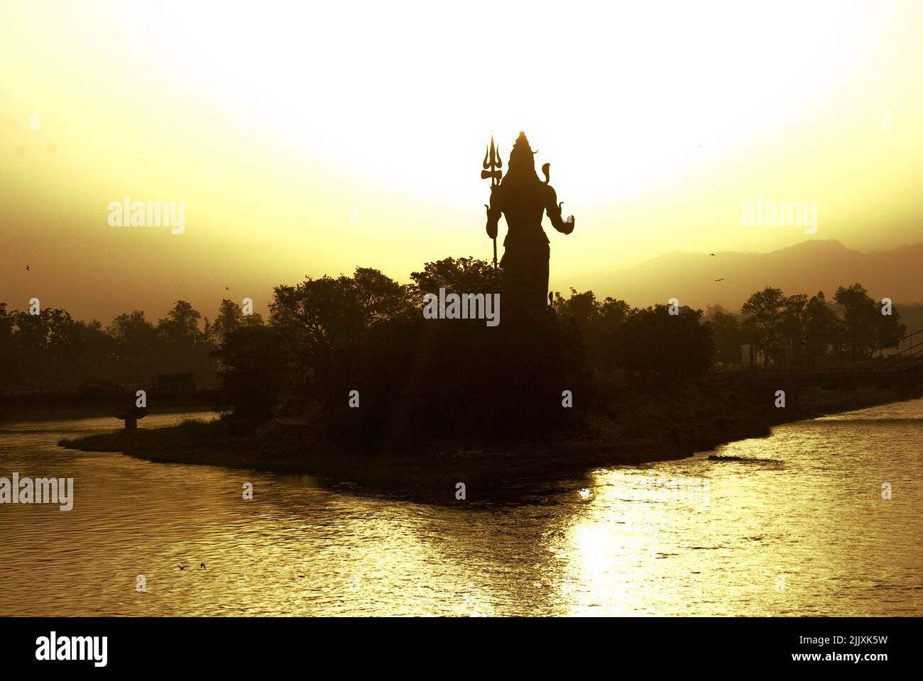 Statua di Lord Shiva che domina Haridwar città Santa in India al sorgere del sole d'oro.situato ai piedi delle montagne Himalayane sulla riva del fiume Gange Santo. Foto Stock