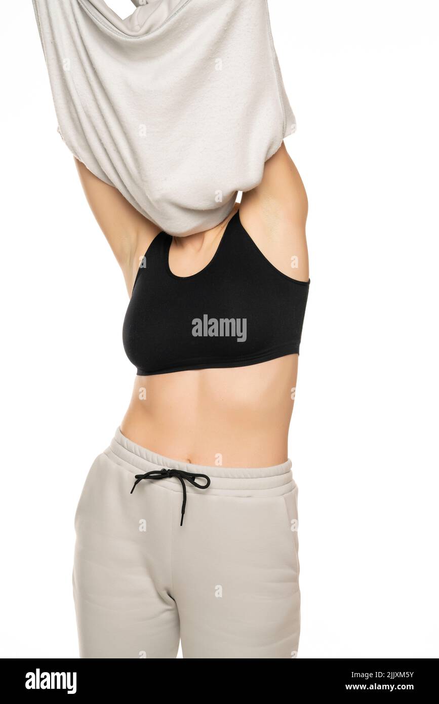 la donna toglie la parte superiore della tuta su sfondo bianco. Foto Stock