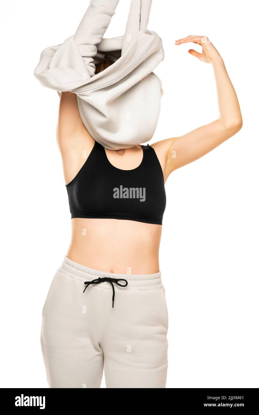 la donna toglie la parte superiore della tuta su sfondo bianco. Foto Stock