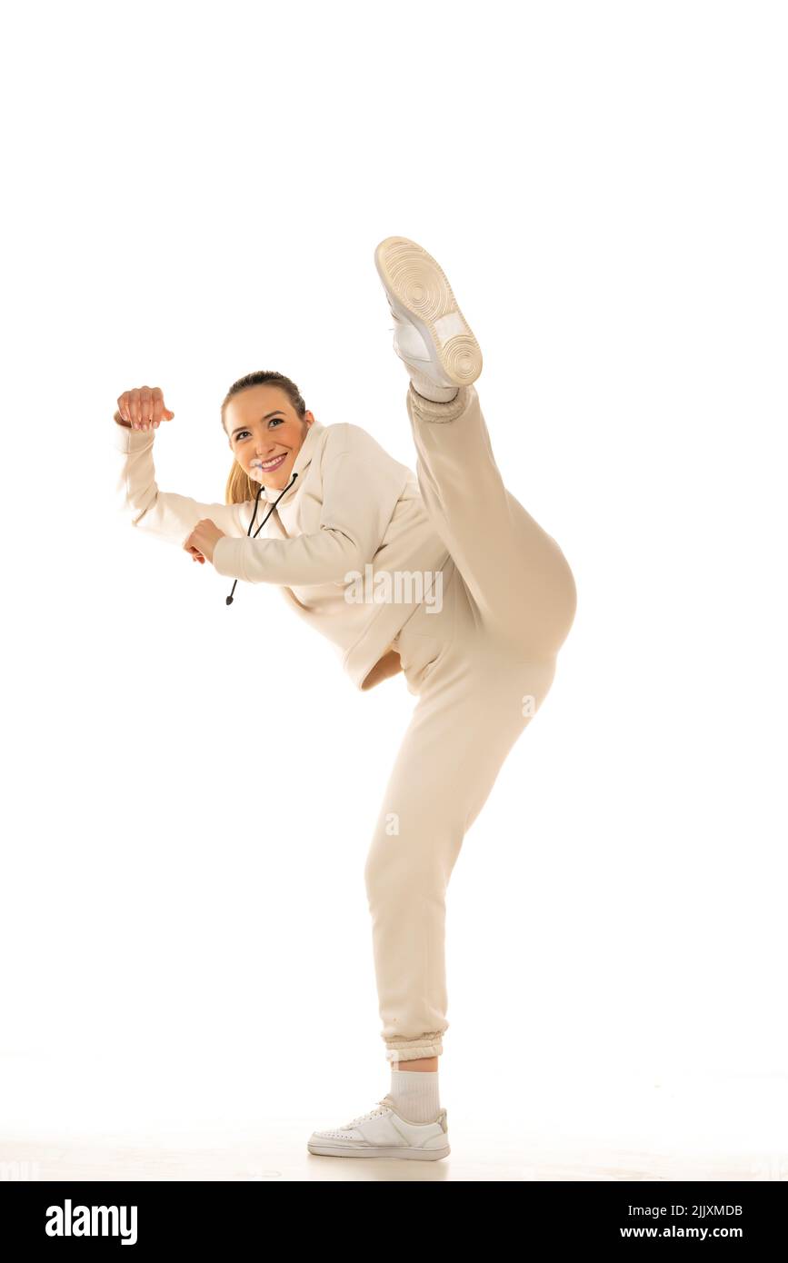 Bella donna sportiva in tuta pratica arte marziale su sfondo bianco. Foto Stock