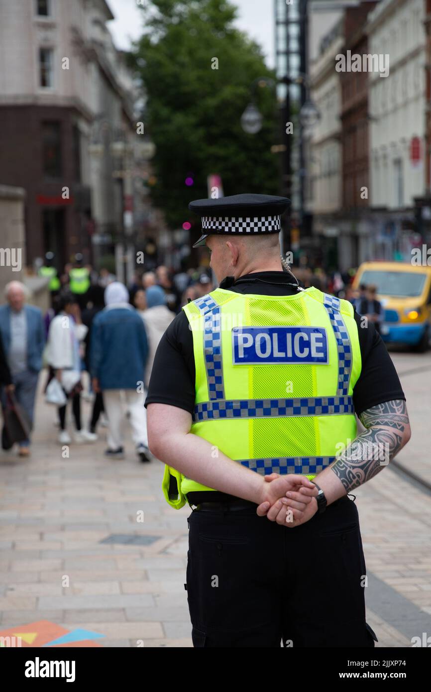 BIRMINGHAM, REGNO UNITO - 28 LUGLIO 2022. Una vista posteriore di un poliziotto in uniforme e con tatuaggi sulla strada di una città del Regno Unito Foto Stock