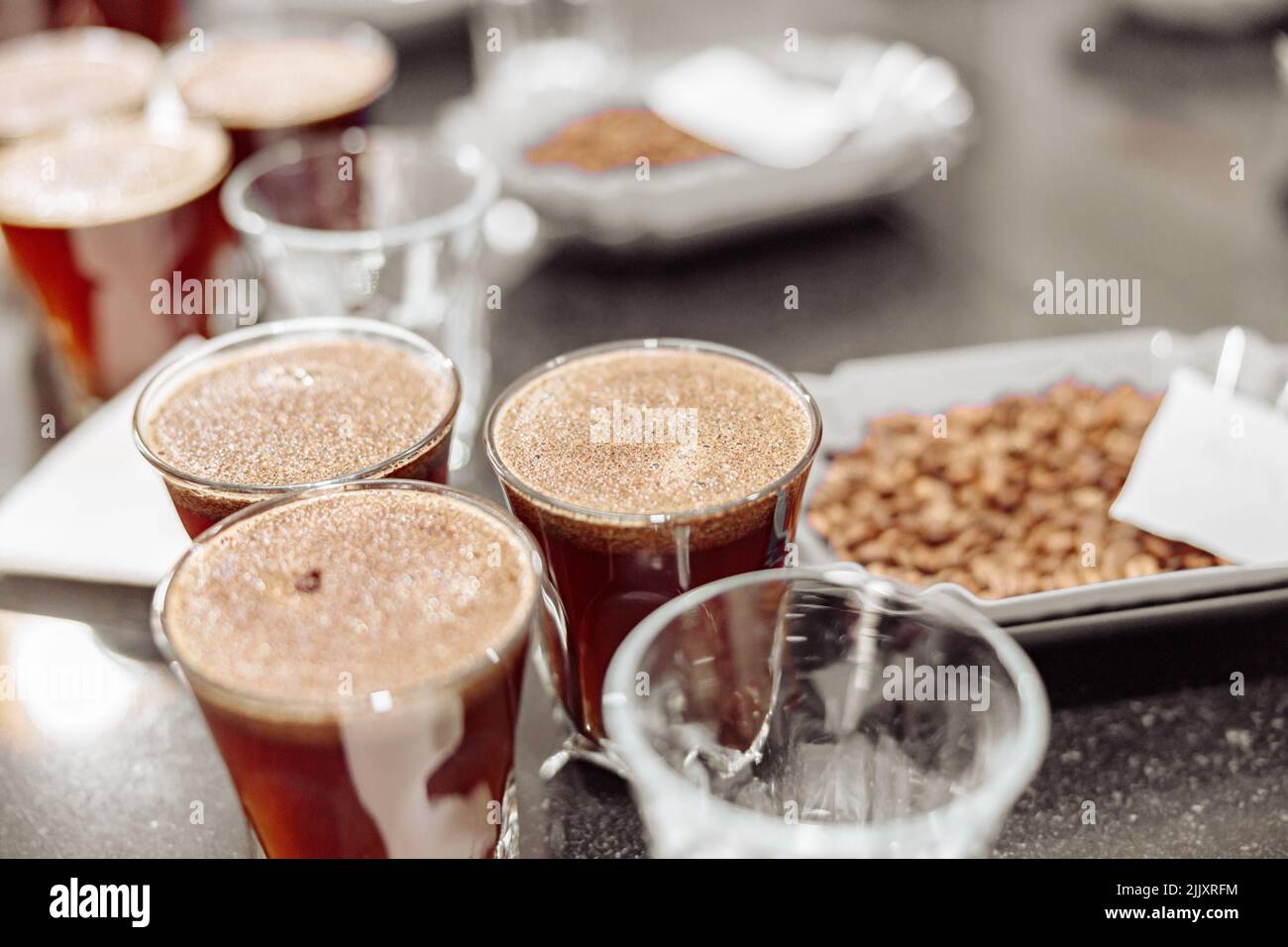 Bicchieri di caffè e ciotole con chicchi di caffè appena tostati Foto Stock
