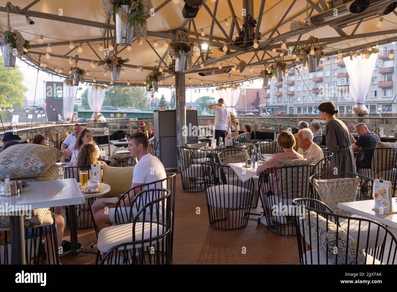 Ristorante Lituania; persone sedute a mangiare in un ristorante su una barca ormeggiata nel porto di Klaipeda, Klaipeda, Lituania, Europa Foto Stock