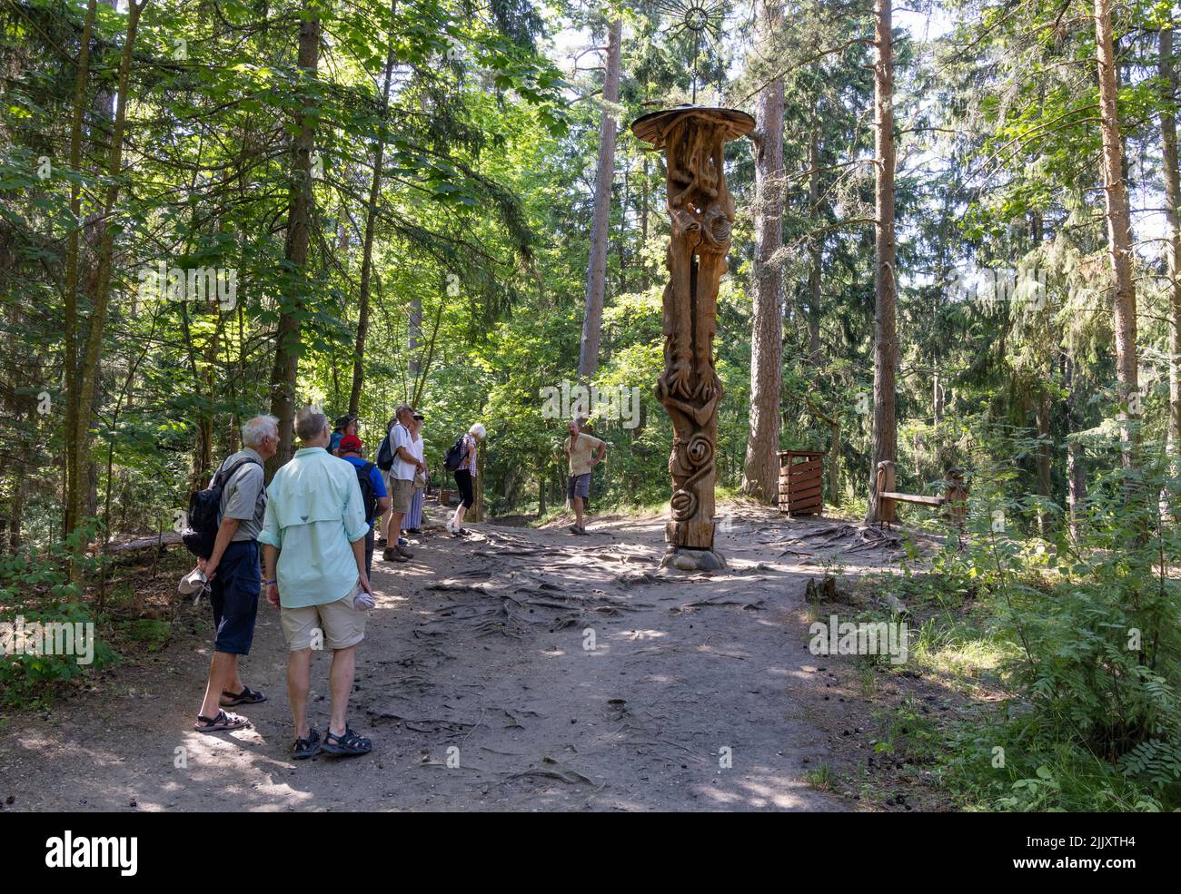 I turisti lituani; gruppo turistico presso il sentiero della scultura della collina delle streghe, statue in legno folklore all'aperto; Parco Nazionale delle Spit Curoniane, Lituania Foto Stock