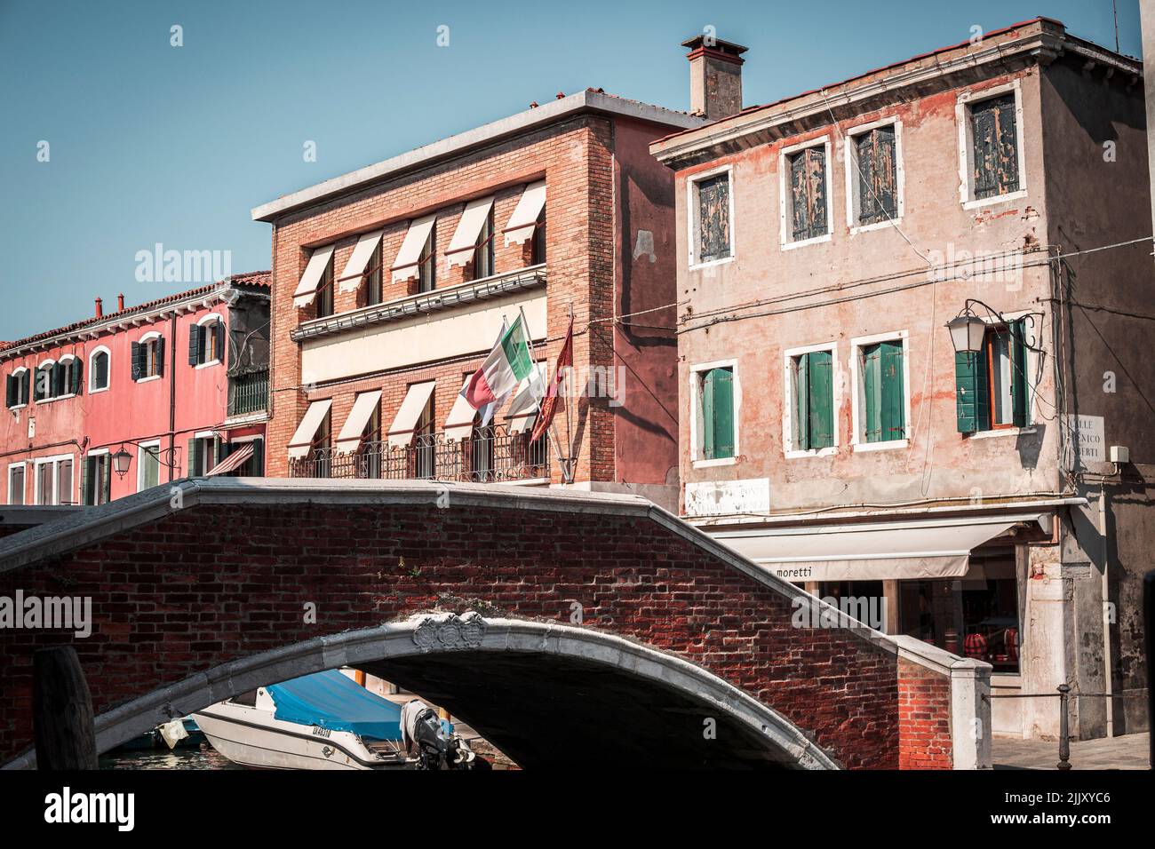 Vista su un piccolo ponte e su edifici sullo sfondo con bandiere italiane a Venezia Foto Stock
