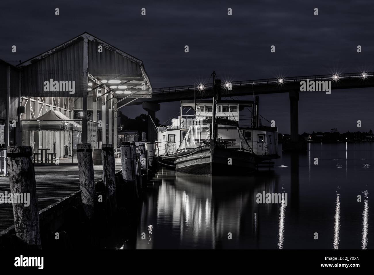 Un'immagine in scala di grigi di un porto con una bella barca sullo sfondo del ponte dell'isola di Hindmarsh Foto Stock