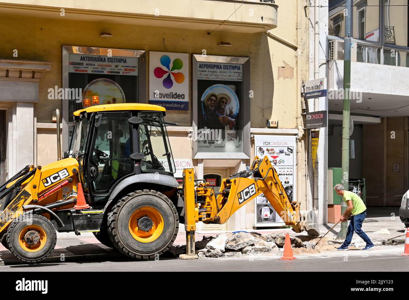 Atene, Grecia - Giugno 2022: Persona scavando la strada nel centro della città con l'aiuto di un scavatore meccanico Foto Stock