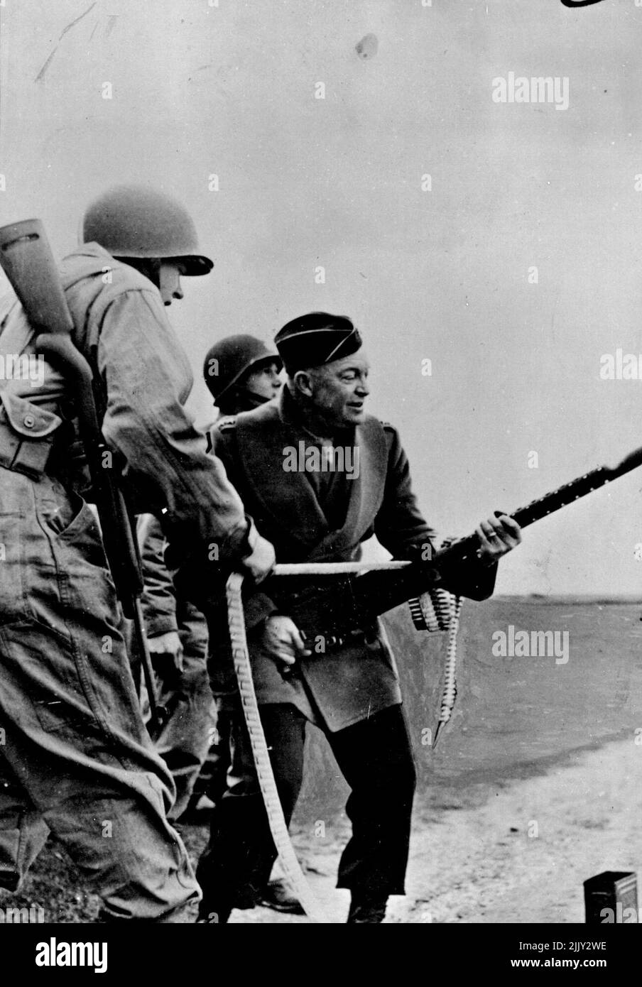 Eisenhower, comandante in capo della forza militare alleata in Gran Bretagna, spara una mitragliatrice non montata dal suo fianco mentre i fanti degli Stati Uniti osservano durante una recente ispezione delle unità dell'esercito alleato in Inghilterra. Marzo 20, 1944. Foto Stock
