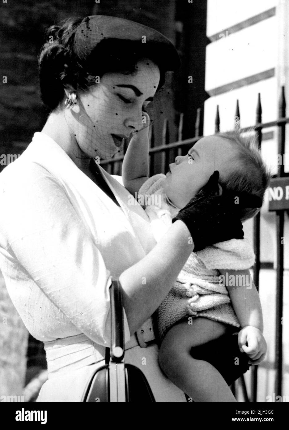 Parte madre e bambino per la prima volta - e fa male. Elizabeth Taylor, parti per un esteso tour europeo con i suoi mariti Michael Wilding, innesti Michael Howard Wilding, otto mesi fa. Più tardi lasciò che l'infermiera lo portasse, mentre si affrettò all'aeroporto di Londra per il suo aereo. Settembre 9, 1953. Foto Stock