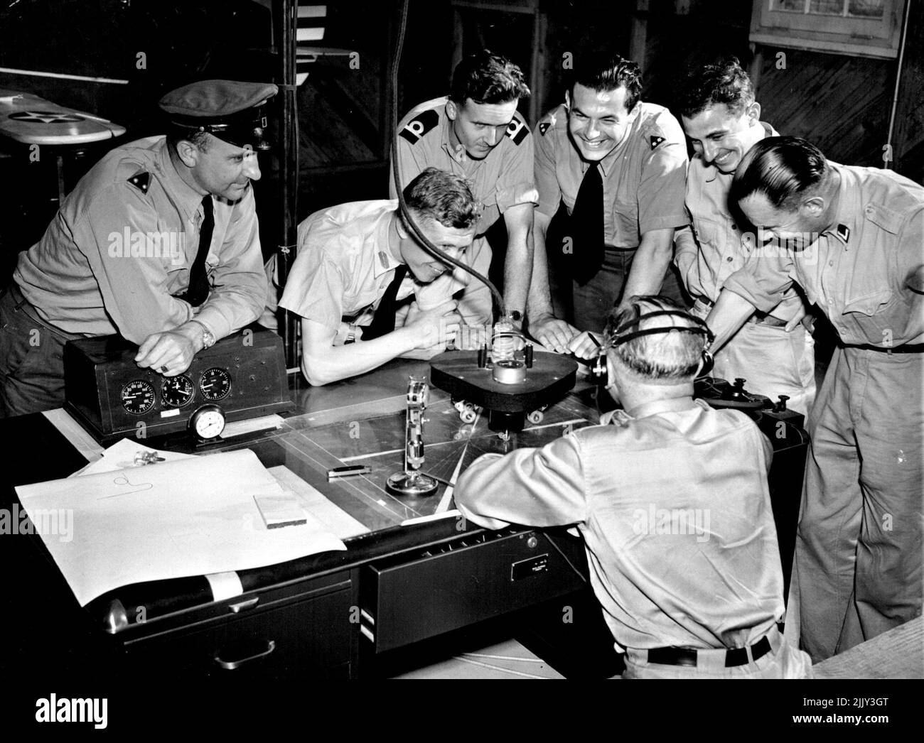 I piloti olandesi Fly 'The Beam' -- un gruppo di studenti olandesi in formazione a Jackson, Miss., si riuniscono intorno alla tabella di registrazione del link formatore volante cieco (in background) e guardano il corso volato da uno dei loro compagni che è 'sotto il cofano' nel formatore. Giugno 16, 1942. (Foto di stampa associata). Foto Stock