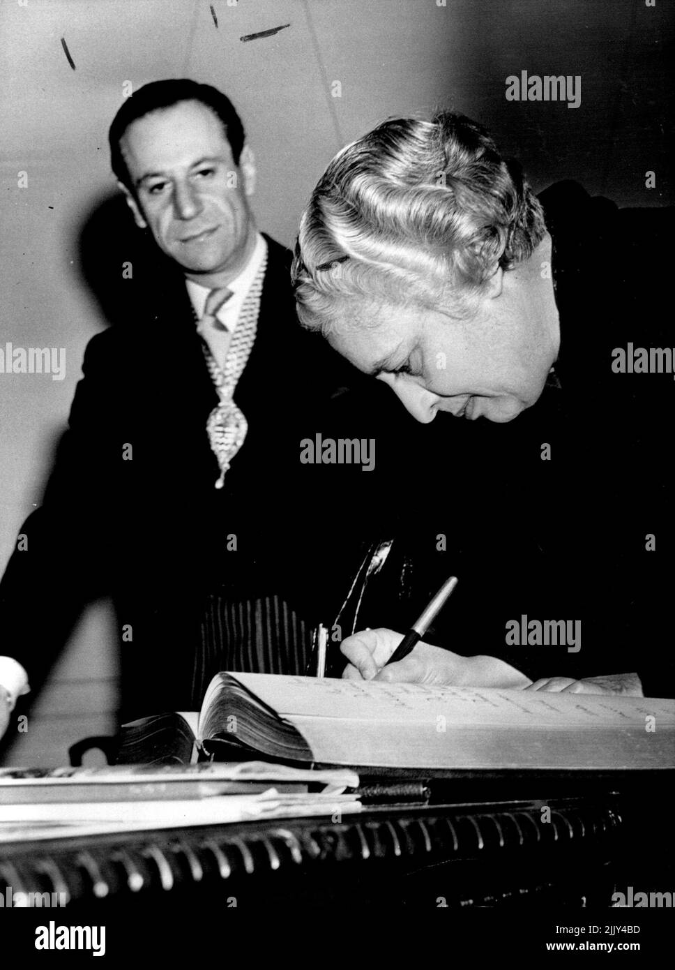 Sig.ra Pandit presso il County Hall. La sig.ra Pandit, oggi, canti il libro dei visitatori al salone di campagna, guardato dal sig. Victor Mishcon, presidente del LCC. La sig.ra Pandit, presidente indiano dell'Assemblea generale delle Nazioni Unite, che si trova in una visita di cinque giorni in Gran Bretagna, ha visitato la sede del consiglio nazionale di Londra presso il municipio di Westminister, questa mattina per vedere la mostra "Scuole speciali". Quando la sig.ra Pandit, sorella di Nehru, primo ministro indiano, tornerà accanto a questo paese, verrà come ambasciatrice indiana. Luglio 8, 1954. (Foto di Paul Popper, Paul Popper Ltd.). Foto Stock