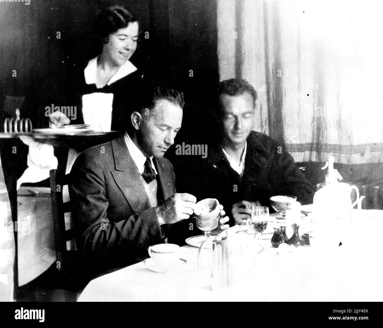 Una colazione americana sul suolo inglese dopo Flying the Atlantic Clyde Pangborn, a sinistra e Hugh Herndon godendo il loro primo vero pasto dopo aver volato attraverso l'Atlantico nel loro aereo 'Miss Veedol'. Questa foto è stata scattata a Croydon dove si sono fermati dopo una breve visita in Galles. Restarono a Croydon solo un breve periodo prima di continuare il loro tentativo di circondare il mondo. Dopo aver raggiunto la Siberia, abbandonarono il volo circolare del globo. Agosto 07, 1931. (Foto di International Newsreel). Foto Stock
