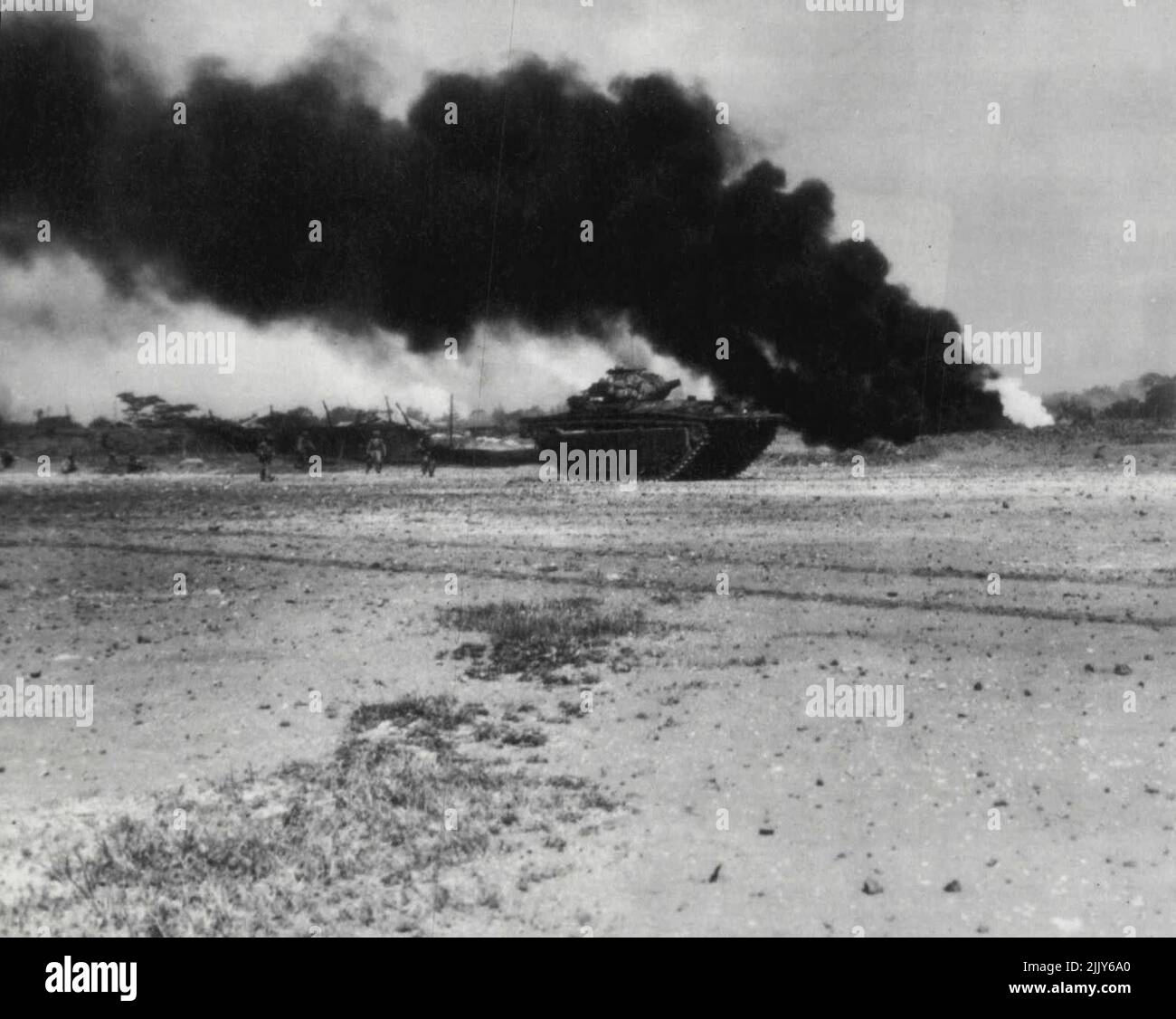 I Marines avanzano su Okinawa: Dietro un carro armato anfibio, i marines degli Stati Uniti avanzano al bordo della striscia aerea di Yontan su Okinawa nel Ryukyus poco dopo l'atterraggio di aprile 1. Un serbatoio di gas sotterraneo sta bruciando sullo sfondo. Aprile 08, 1945. (Foto di AP Wirephoto). Foto Stock