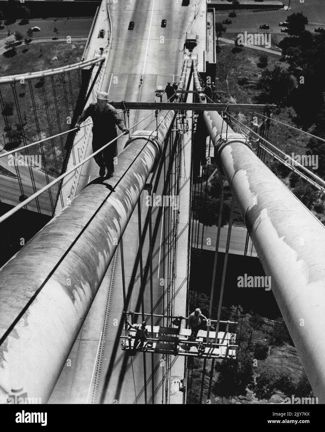 Up in the Air -- Carol G. Warren, un rigger e uno dei sessanta uomini che dipingono il George Washington Bridge che collega New York City e New Jersey, si aggrappa strettamente ai corrimano mentre cammina su uno dei cavi del ponte, luglio 26. Affrontando una goccia di 260 - 600 piedi se scivolano, i pittori sono previsti per prendere quattro anni al loro compito. Rimandato durante la guerra a causa della scarsità di vernice, il lavoro costerà $400.000. Agosto 26, 1946. (Foto di stampa associata). Foto Stock