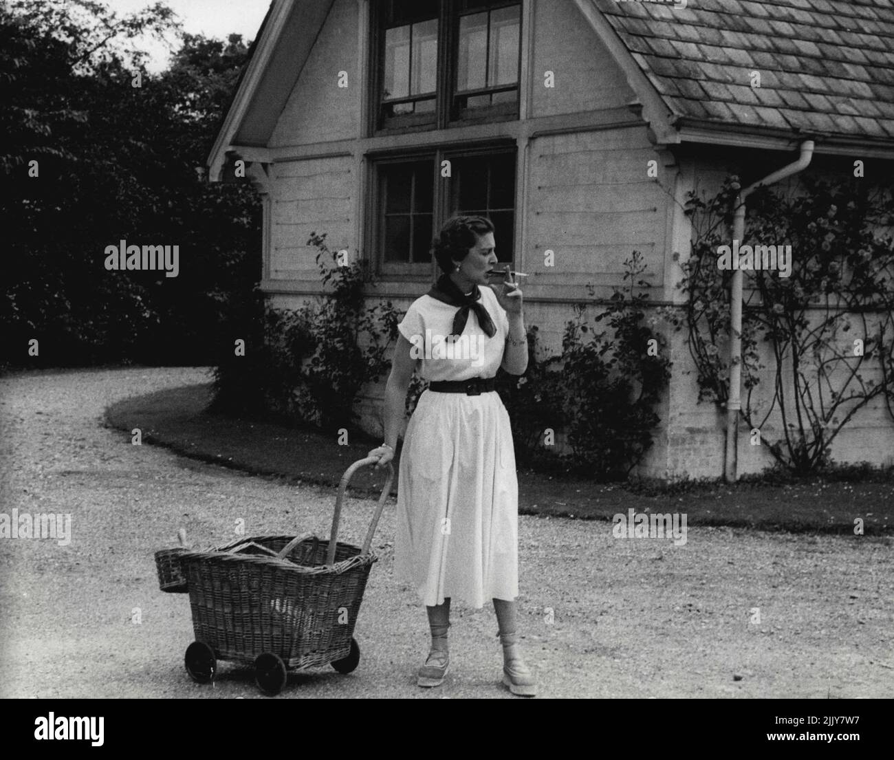 La duchessa di Kent e sua figlia, la principessa Alexandra - la duchessa di Kent con il carrello di giardinaggio di vimini-lavoro, fa una pausa per fumare una sigaretta mentre aspetta sua figlia. Settembre 7, 1954. (Foto di Michael Mckeown). Foto Stock