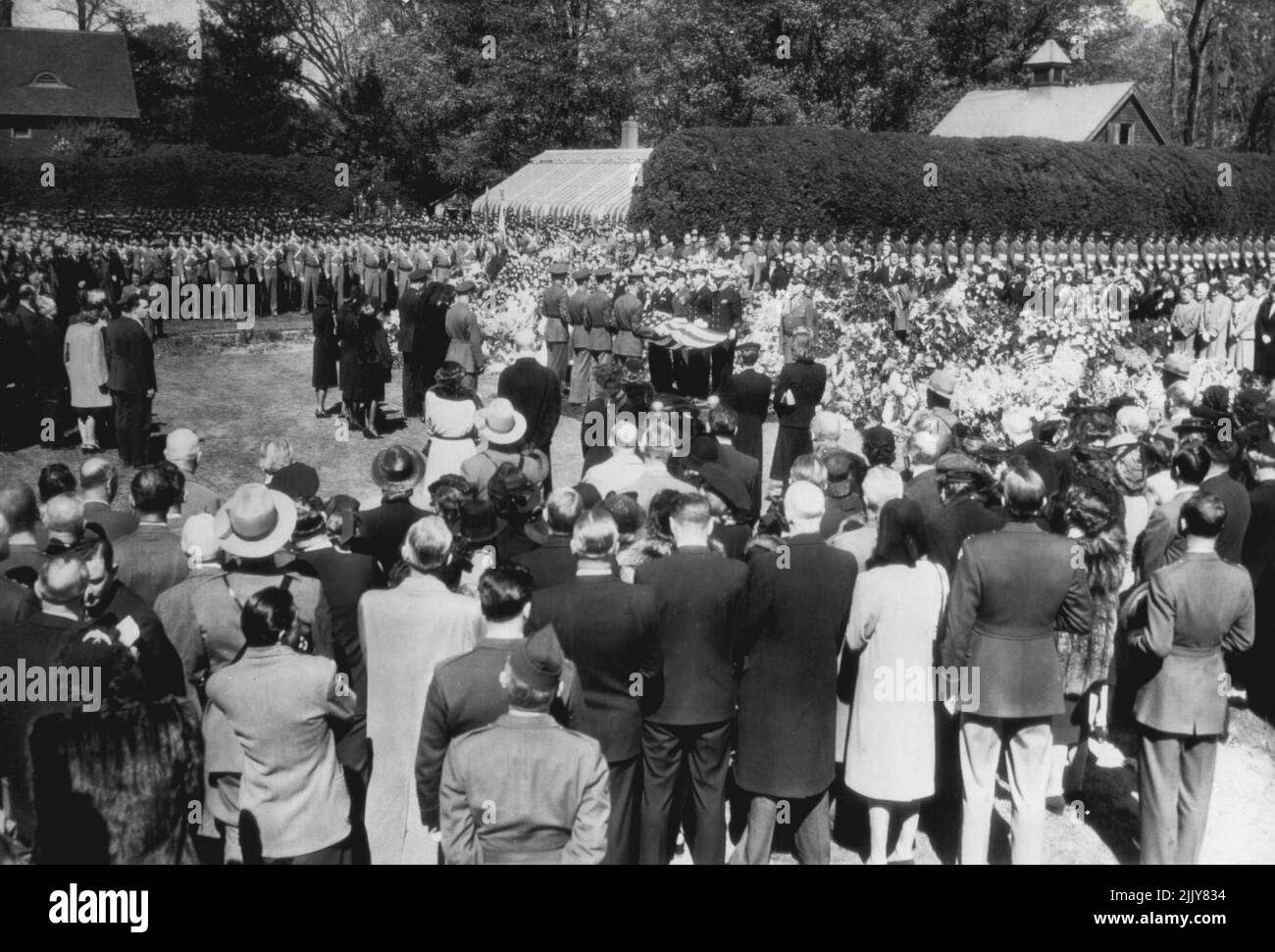 Roosevelt coffin è abbassato in grave - la bara che contiene il corpo del defunto presidente Franklin D. Roosevelt cade lentamente in una tomba nel giardino dei fiori di is proprietà sulle rive del fiume Hudson qui come i militari tenere una bandiera americana sul posto. A sinistra della tomba in prima fila sono (da sinistra a destra) Briga. Gen. Elliott Roosevelt, Sig.ra Roosevelt, Anna Roosevelt Boettiger e col. John Boettiger. Dietro di loro c'è il defunto presidente quattro nuora. Più indietro all'estrema sinistra ci sono il presidente Truman. La signora Truman e la loro figlia. Aprile 15, 1945. (Foto di AP Wirephoto). Foto Stock