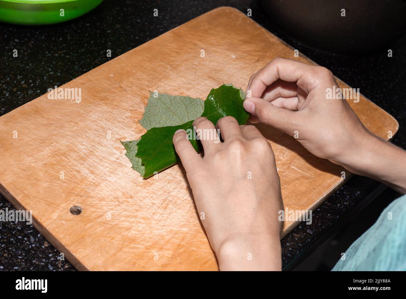 Il ragazzo sta imparando a cucinare. Un bambino avvolge la carne macinata in una foglia d'uva per produrre la dolma. Foto Stock
