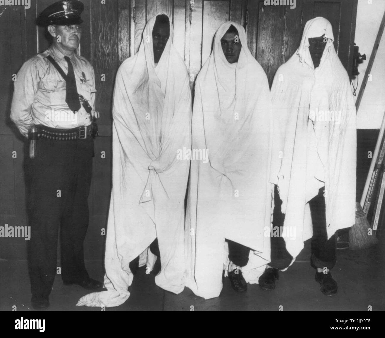 Caricato con la legge anti-maschera dell'Alabama -- capo della polizia di Ozark, Hoyt Searcy, si trova accanto ai tre incaricati di violare la nuova legge anti-mascheramento dell'Alabama. Due delle imputazioni di ieri hanno dichiarato colpevoli le accuse e sono state condannate in carcere. Il terzo sarà provato oggi. Le cariche sono (da sinistra a destra) Tommie Johnson, 19; Raymond McClendon, 20, e Robert Miller, 21. Johnson e Miller ammisero di formare il loro 'Klavern', indossando lenzuola bianche e spaventando tre ragazze luglio 14. Agosto 6, 1949. (Foto di AP Wirephoto). Foto Stock