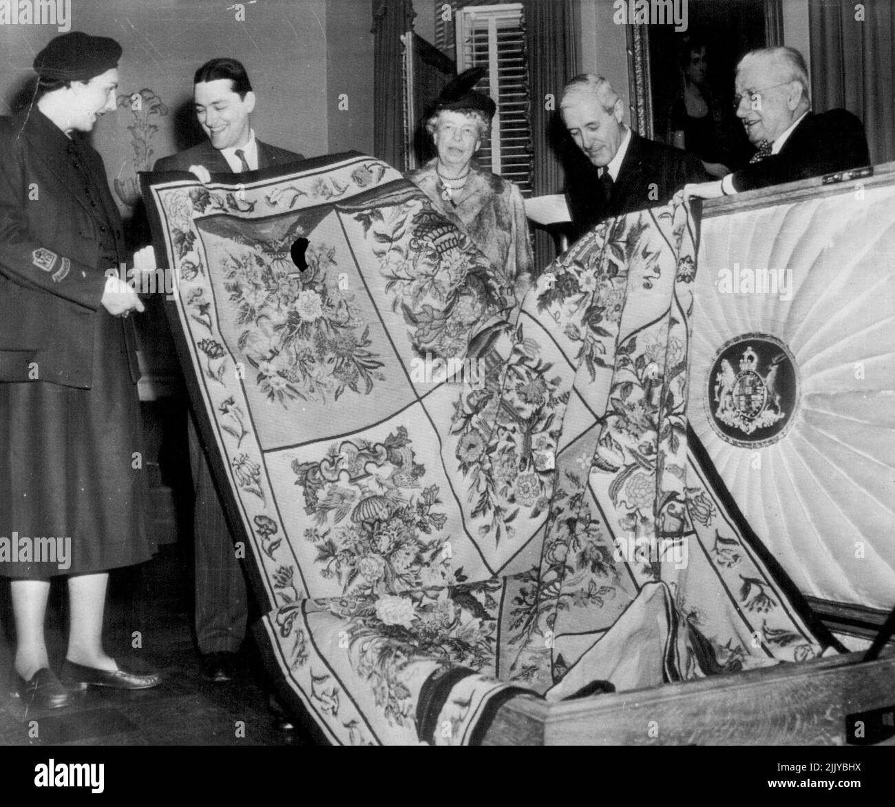 Splay -- Un tappeto fatto dalla Regina Maria d'Inghilterra e donato da lei per la vendita per aiutare a ricostituire il suo paese il magro approvvigionamento di dollari è esposto oggi in anteprima presso la sede dell'Unione di lingua inglese. Da sinistra a destra ci sono Patricia Hardie, custode del tappeto in viaggio dall'Inghilterra a bordo della linea Regina Maria; Philip Young, Capo della filiale di New York dell'Unione; la signora Franklin D. Roosevelt, uno degli ospiti invitati; Sir Francis Evans. Il Console Generale britannico a New York; e il col. Angus McDonne, incaricato di prendere tappeto in giro per le città degli Stati Uniti e del Canada. Marzo 22, 1950. (Foto di AP Wirephoto). Foto Stock