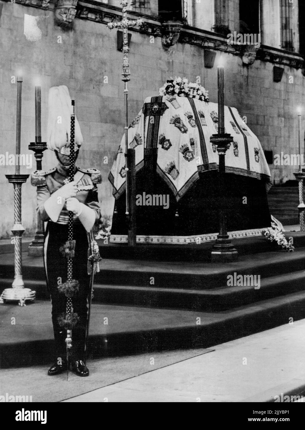 Questa foto mostra la scena nella sala di Westminster questo pomeriggio marzo 29 come la Regina Maria si trova nello stato. In servizio ai piedi della catafalque è un ufficiale della guardia del corpo di sua Maestà del corpo onorato corpo di Gentlemen-at-Arms. Altri in servizio (non mostrati) sono della guardia del corpo della Regina dello Yeomen della Guardia. La Sala è stata aperta al pubblico poco dopo che questa immagine è stata fatta. La menzogna in stato continuerà fino alla mezzanotte di domani. Una coda lunga tre quarti di miglio aspettava che le porte si aprissero. Il funerale si terrà a Windsor il 31 marzo. Marzo 29, 1953. (Foto di stampa associata). Foto Stock