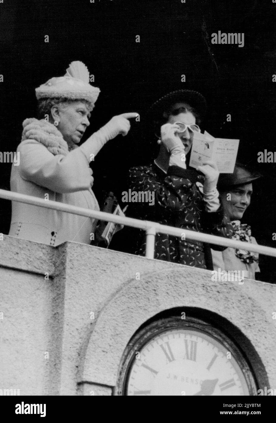 Re e regina e famiglia reale al Derby -- la regina Maria che indica l'incidente alla duchessa di Kent, che sta alzando i suoi vetri scuri per ottenere un sguardo migliore. A destra c'è la duchessa di Gloucester. Il re e la regina e altri membri della famiglia reale hanno ricevuto un grande benvenuto dalla folla di 250.000 persone arrivati a guardare la corsa Derby. Giugno 02, 1937. (Foto di Keystone). Foto Stock