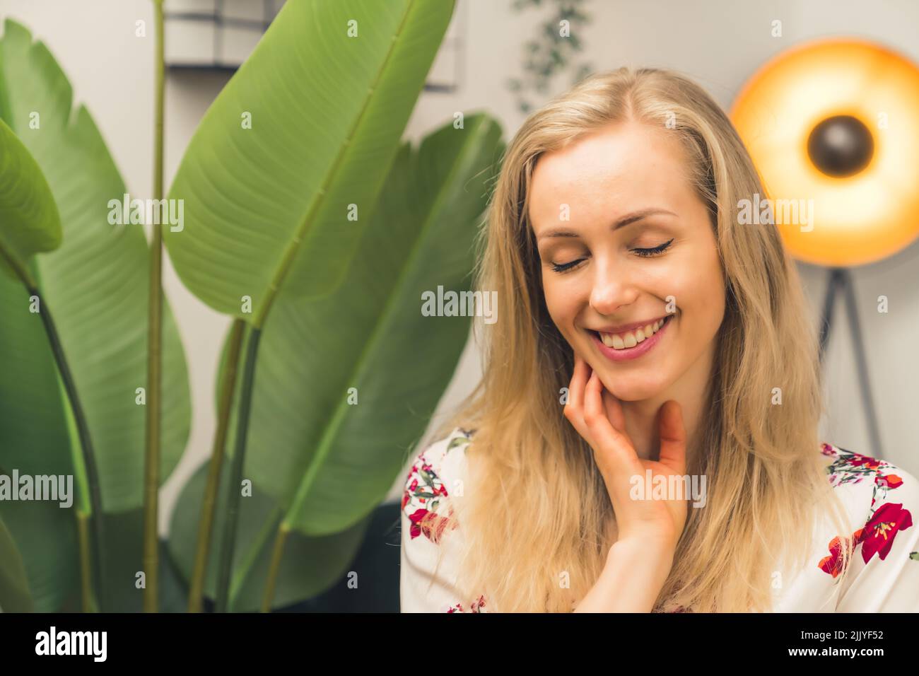 Bionda caucasica sorridente ragazza in una stanza con una pianta. Foto di alta qualità Foto Stock