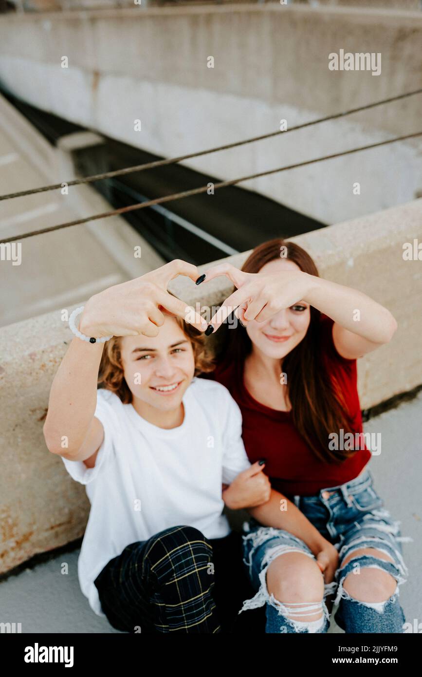 fidanzata e ragazza seduta sul tetto che fa simbolo del cuore Foto Stock