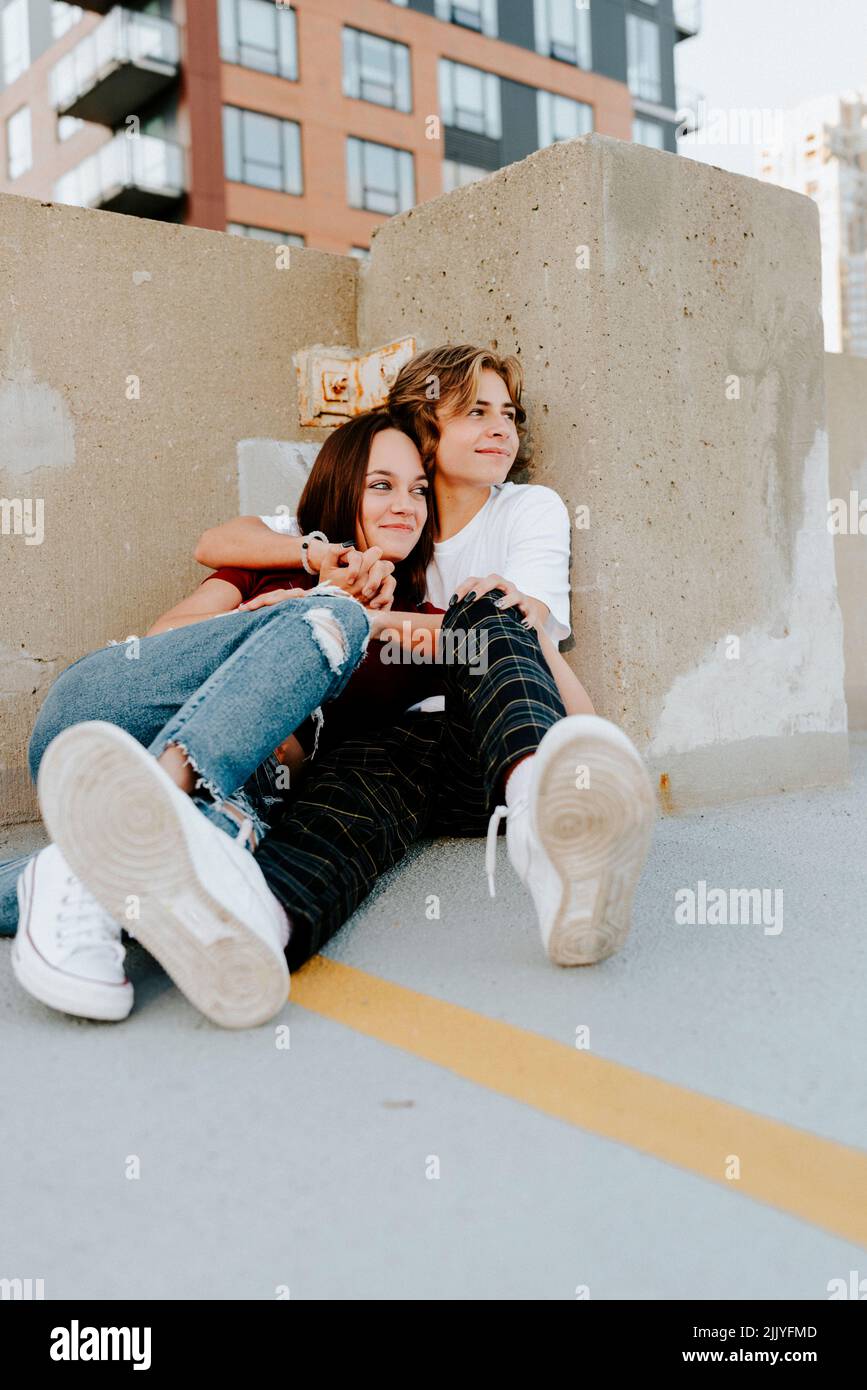 ragazzo e ragazza che abbracciano e guardano via felice Foto Stock