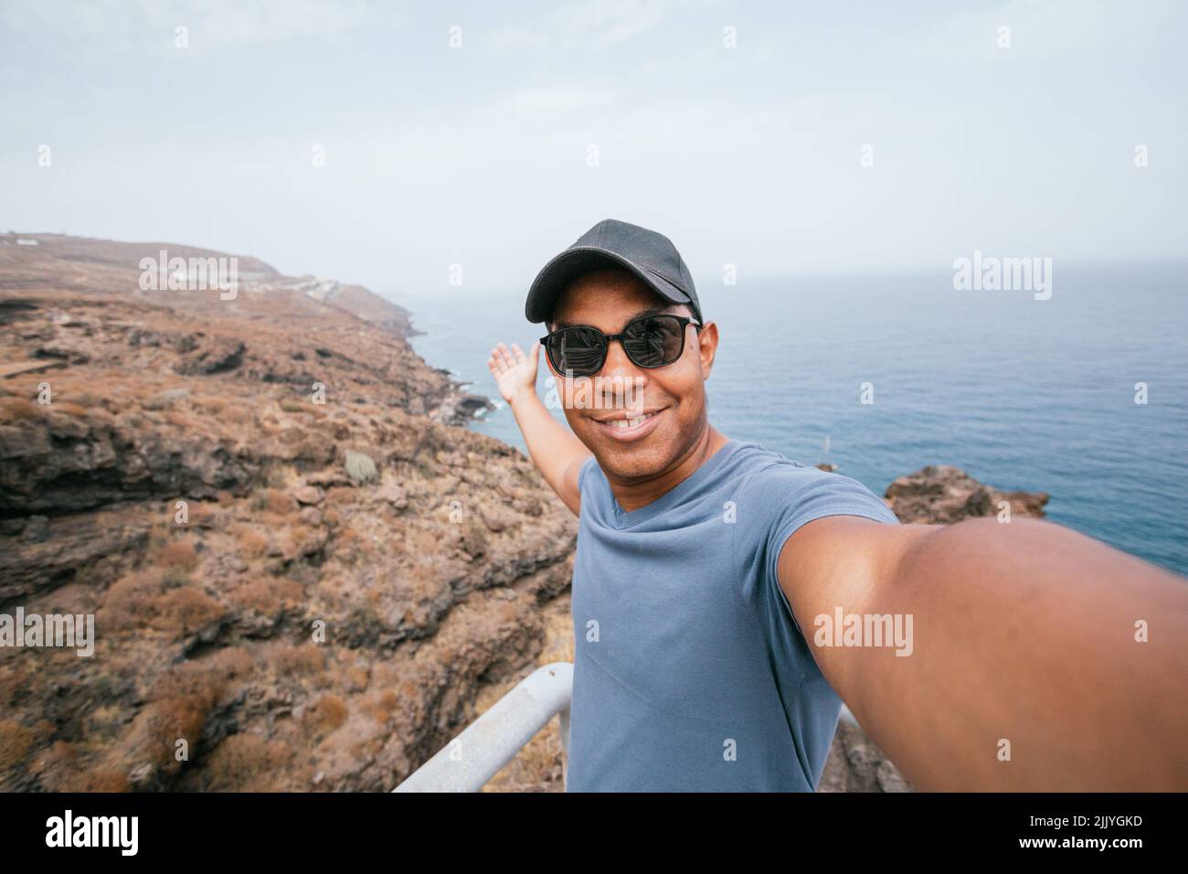 Uomo latino che prende selfie da montagne al largo della costa dell'isola di Tenerife Foto Stock