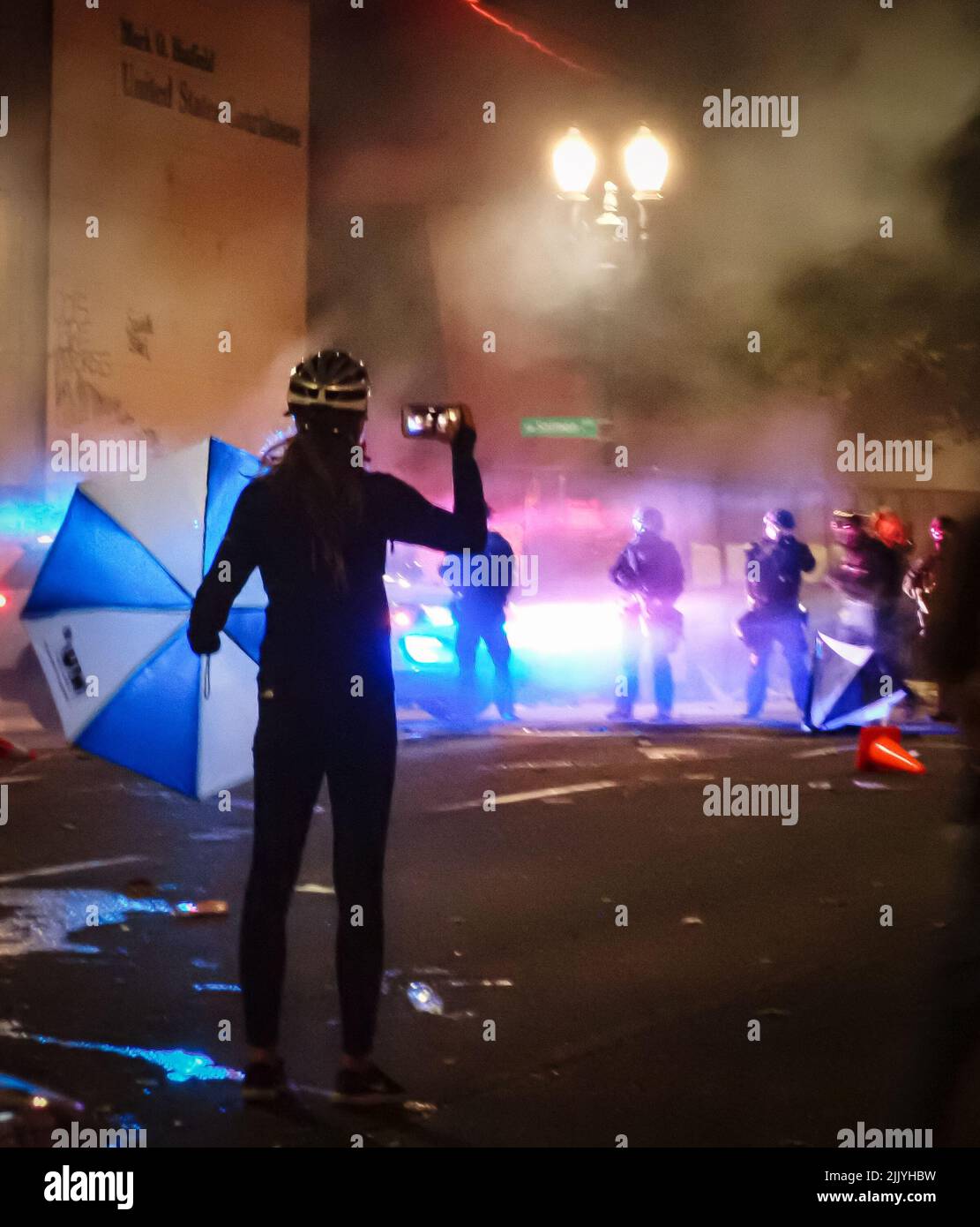 Un protestore filma mentre il dipartimento della polizia di Portland si sposta in strada. Foto Stock
