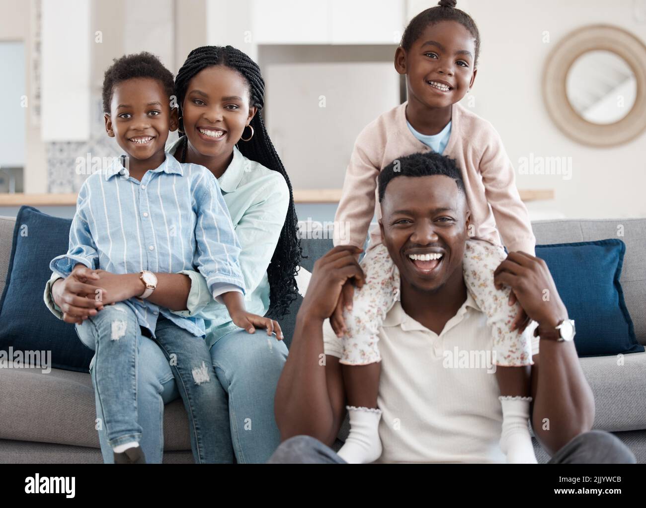 Una famiglia felice. Ritratto corto di una giovane famiglia affettuosa di quattro che si rilassa nel soggiorno di casa. Foto Stock