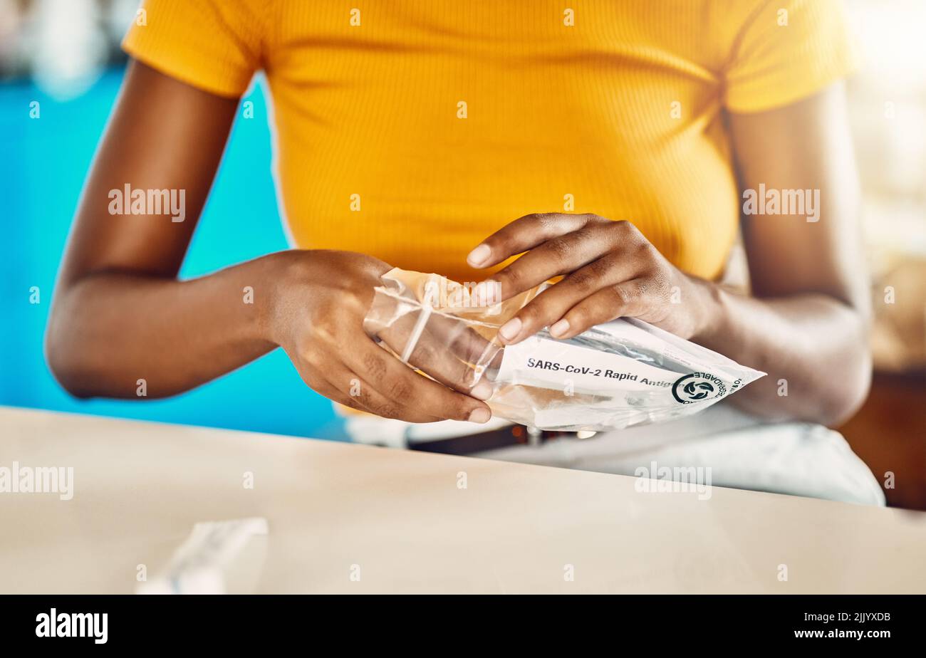 Test per covid, corona virus o infezione con un kit di test rapido antigenico a casa. Primo piano di una donna casual disimballaggio di un kit di screening per diagnosticare un Foto Stock