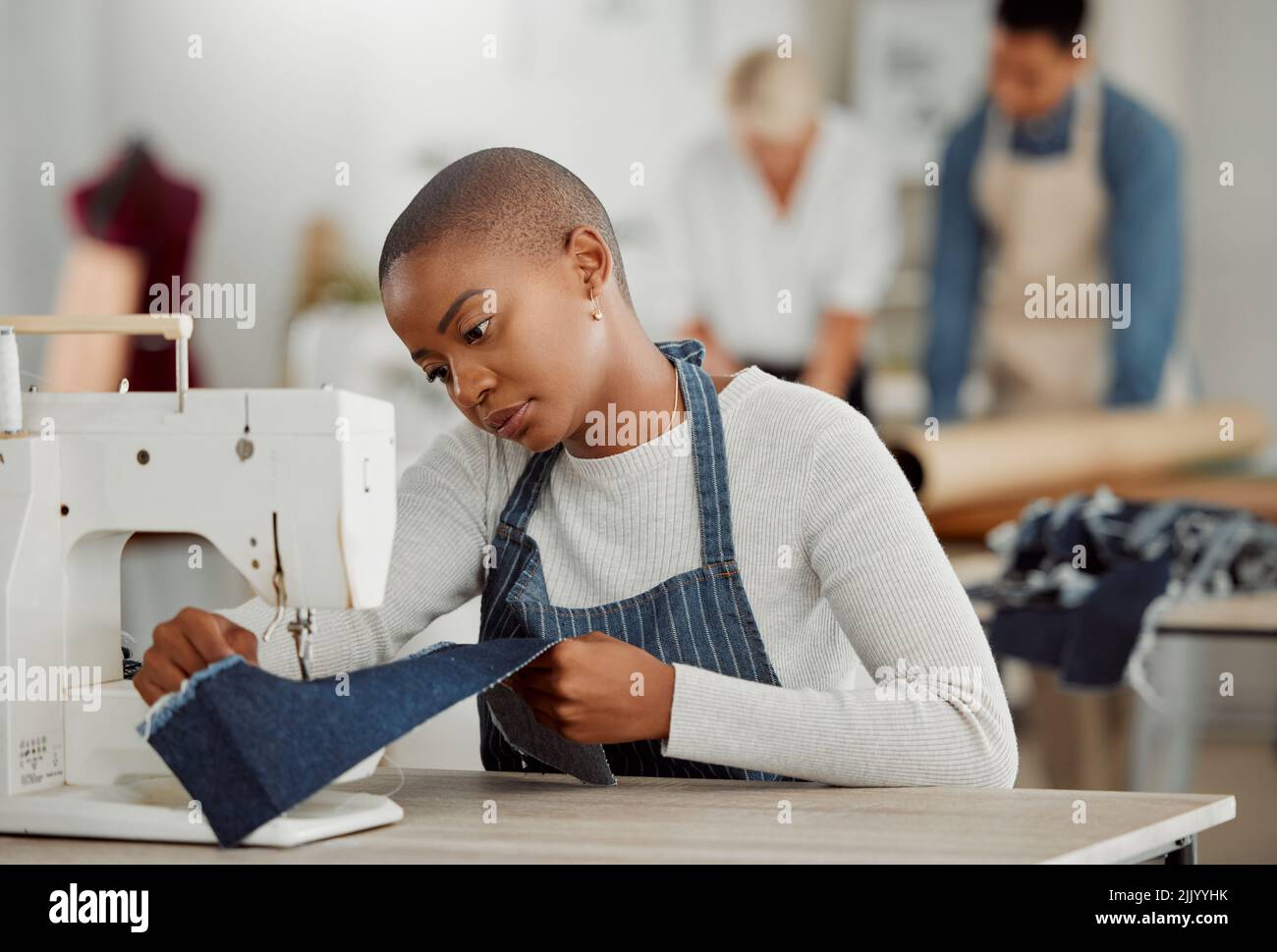 Moda, design e lavoro creativo in un laboratorio. Giovane operaio afro-americano cucito nuovo, alla moda, abbigliamento della stagione. Nero Foto Stock