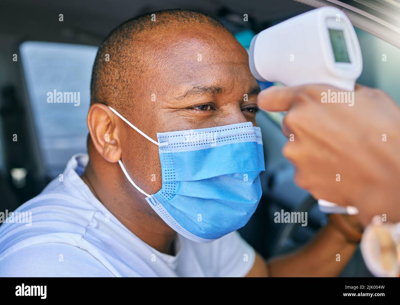 Febbre, temperatura e test Covid alla guida attraverso la stazione in un'auto. Screening del paziente con maschera protettiva con termometro digitale. Benessere e. Foto Stock