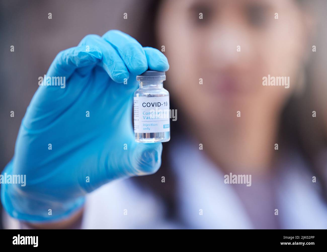 Tenere le generazioni future. Sparo defocused di un medico irriconoscibile che tiene un vaccino del virus della corona fuori. Foto Stock