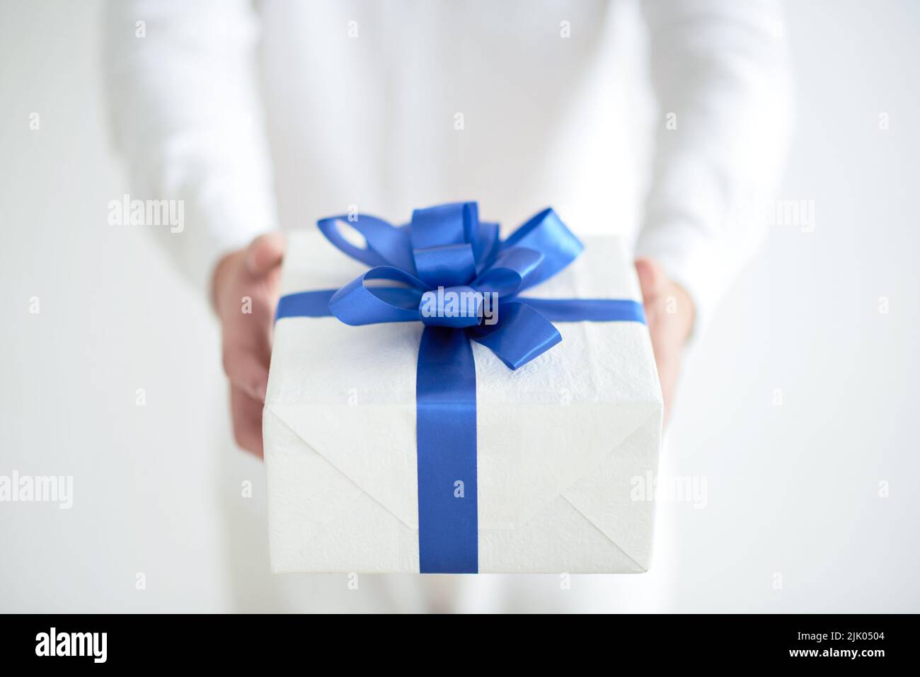 Primo piano immagine del presente con nastro blu nelle mani del giovane uomo Foto Stock