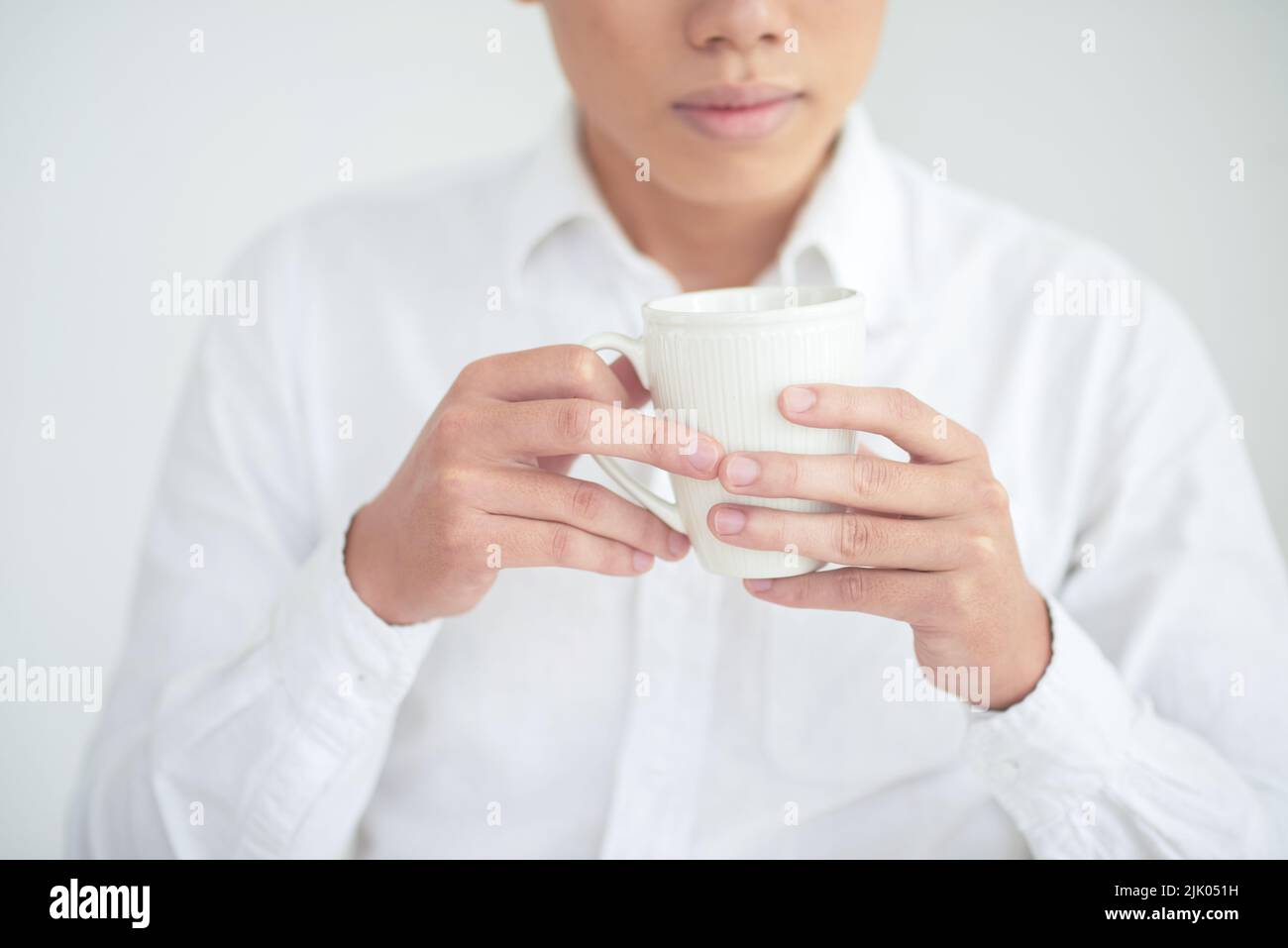 Immagine ritagliata del giovane che tiene una tazza di tè Foto Stock