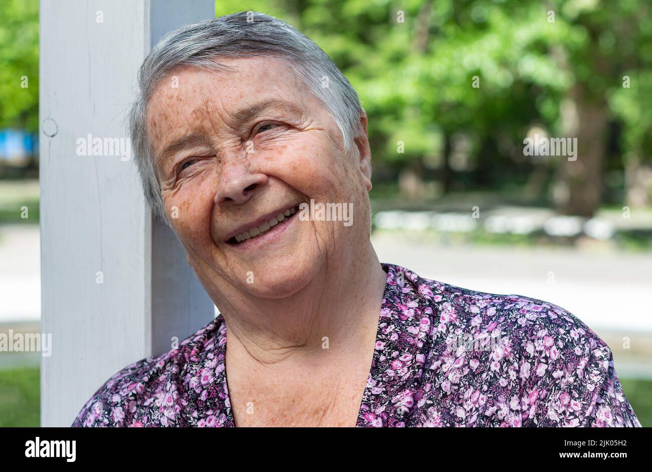 Donna anziana che chiacchiera con gli amici, ride all'aperto. Donna che si diverte a piedi all'aperto in estate, giorno Nazionale dei nonni, diversità, focu selettivo Foto Stock