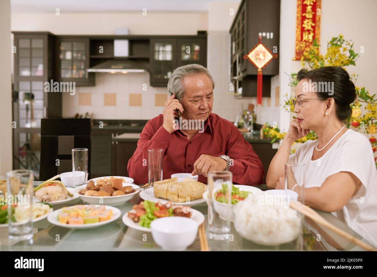 Coppia anziana in attesa dei loro figli e nipoti per la cena di Capodanno cinese. Scorre desiderio di fortuna e ricchezza in background Foto Stock