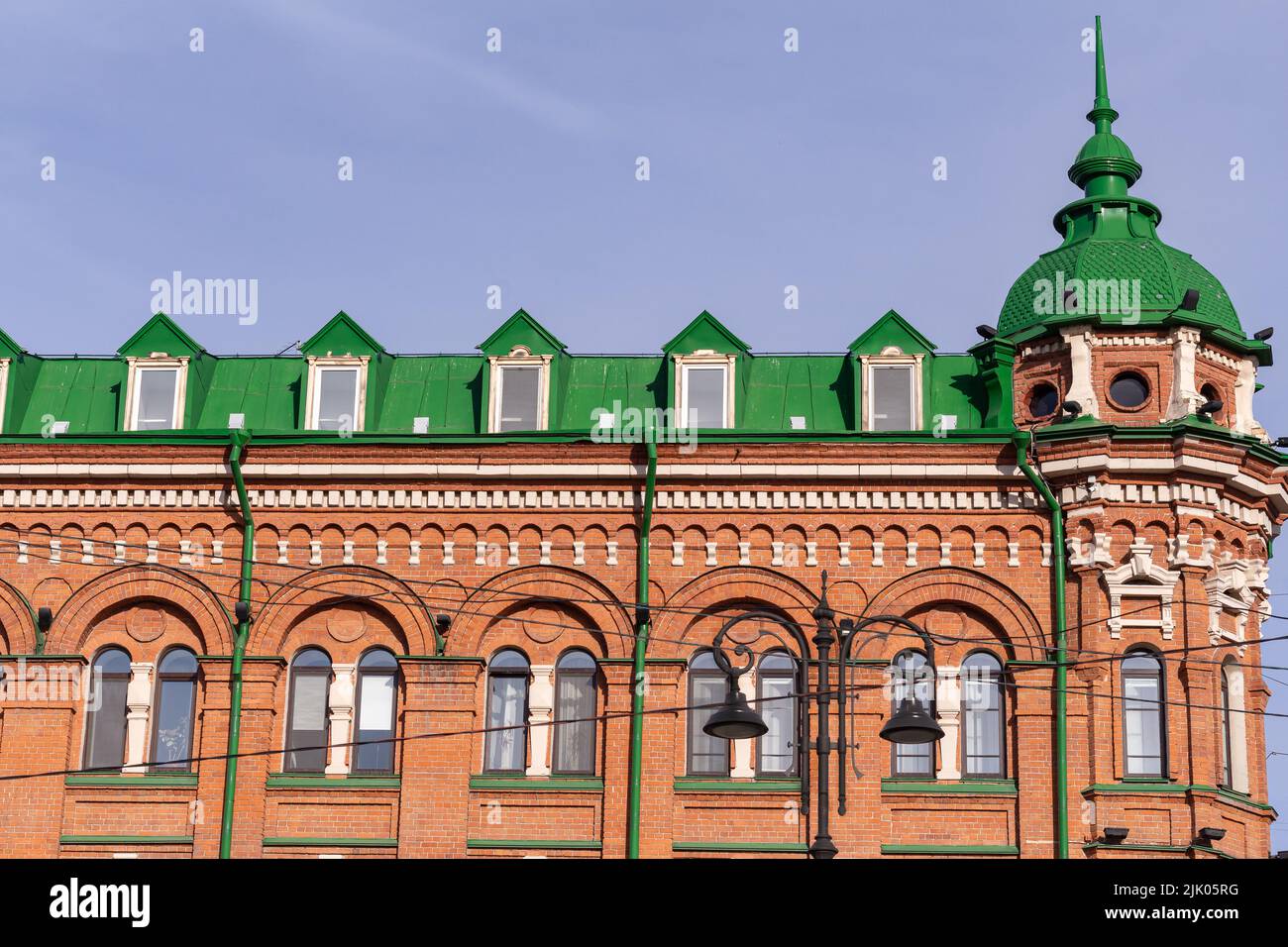 Parte della facciata della Casa di vecchio edificio storico risalente al 1899 con pareti rosse tetto verde.trasformato edificio storico fascino tradizionale. Foto Stock