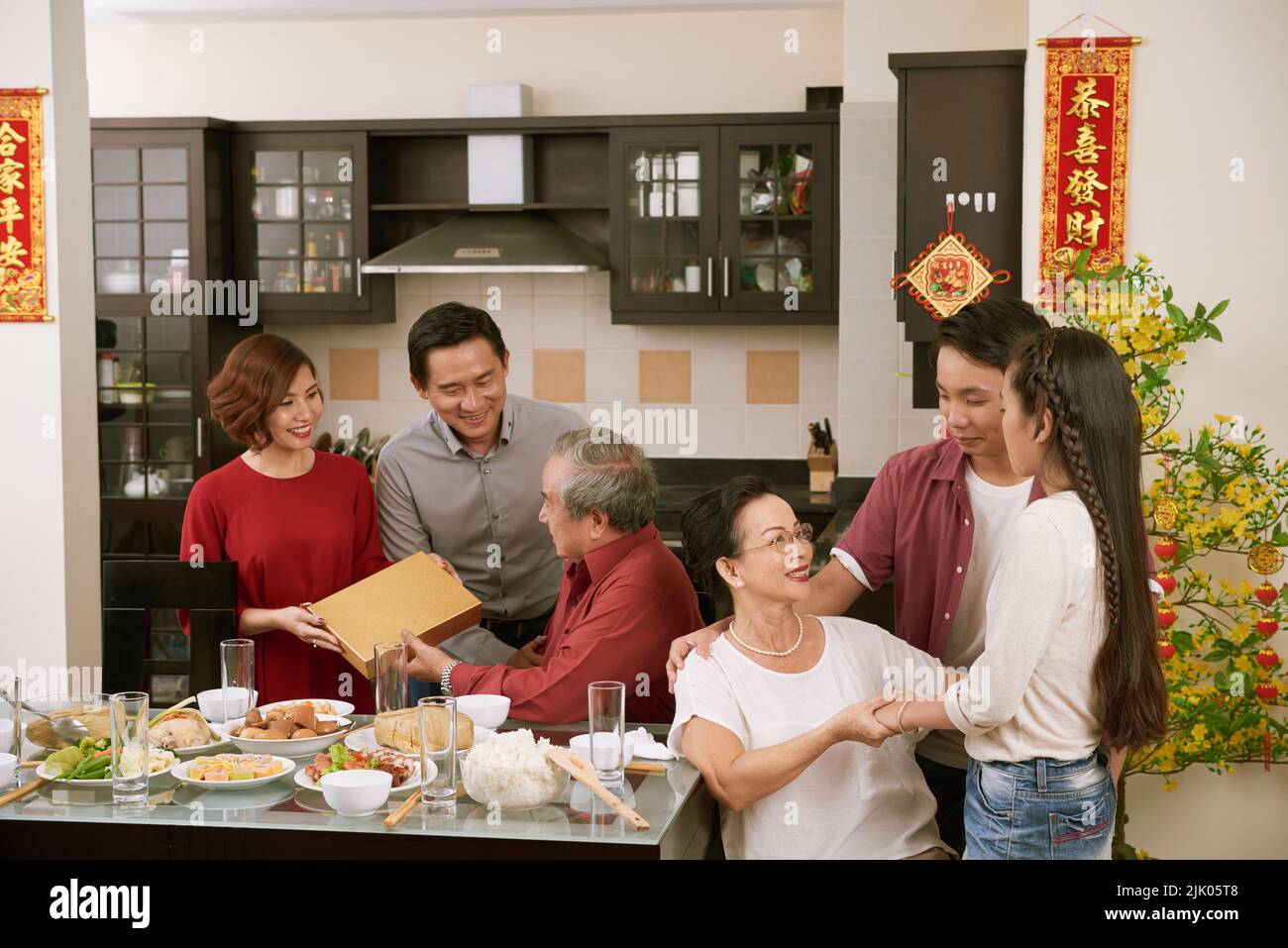 Grande famiglia vietnamita festeggia la festa di primavera a casa. Scorre desiderio di fortuna e ricchezza in background Foto Stock