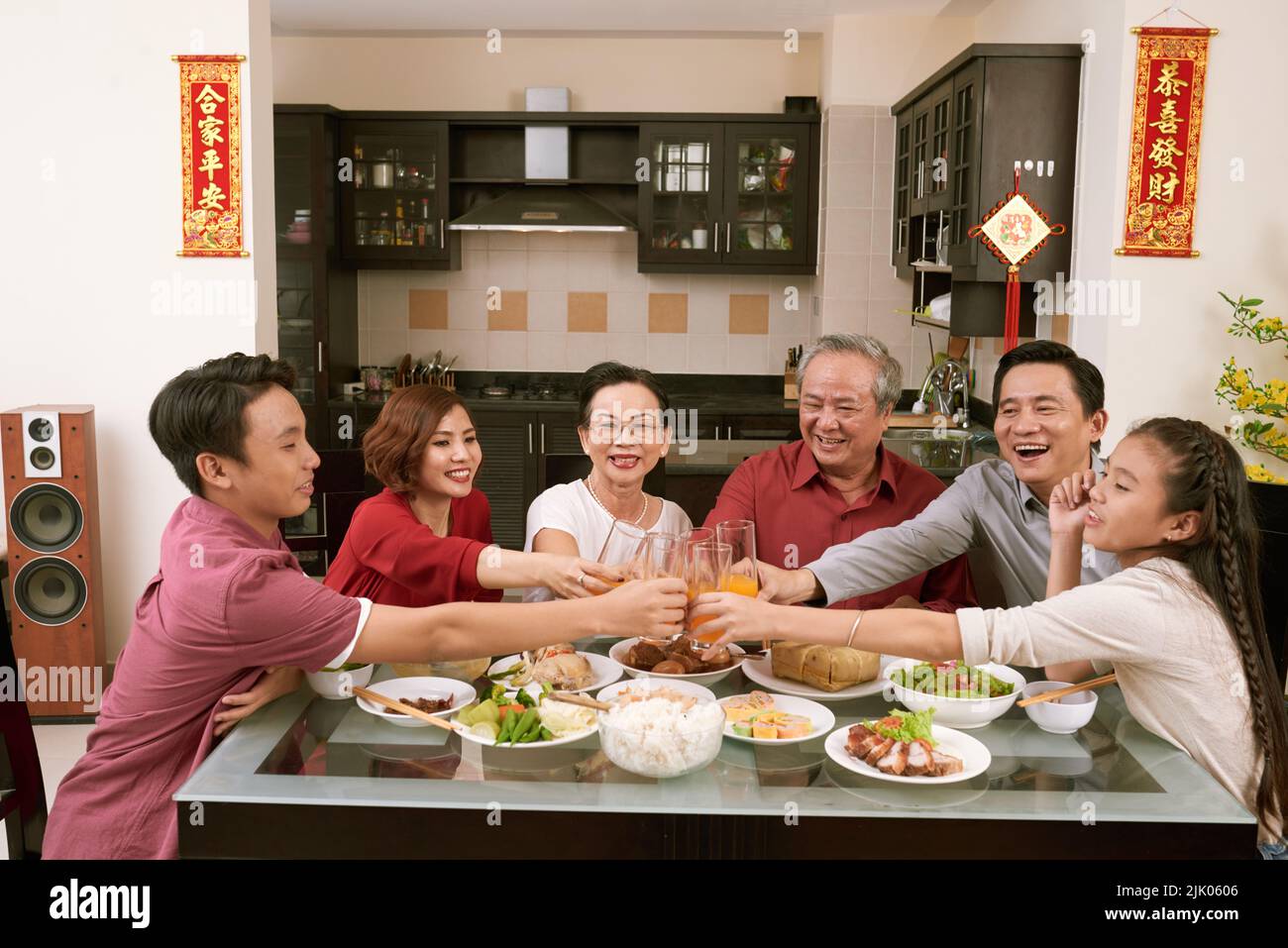 Buona famiglia vietnamita tostatura con bicchieri di succo. Scorre desiderio di fortuna e ricchezza in background Foto Stock