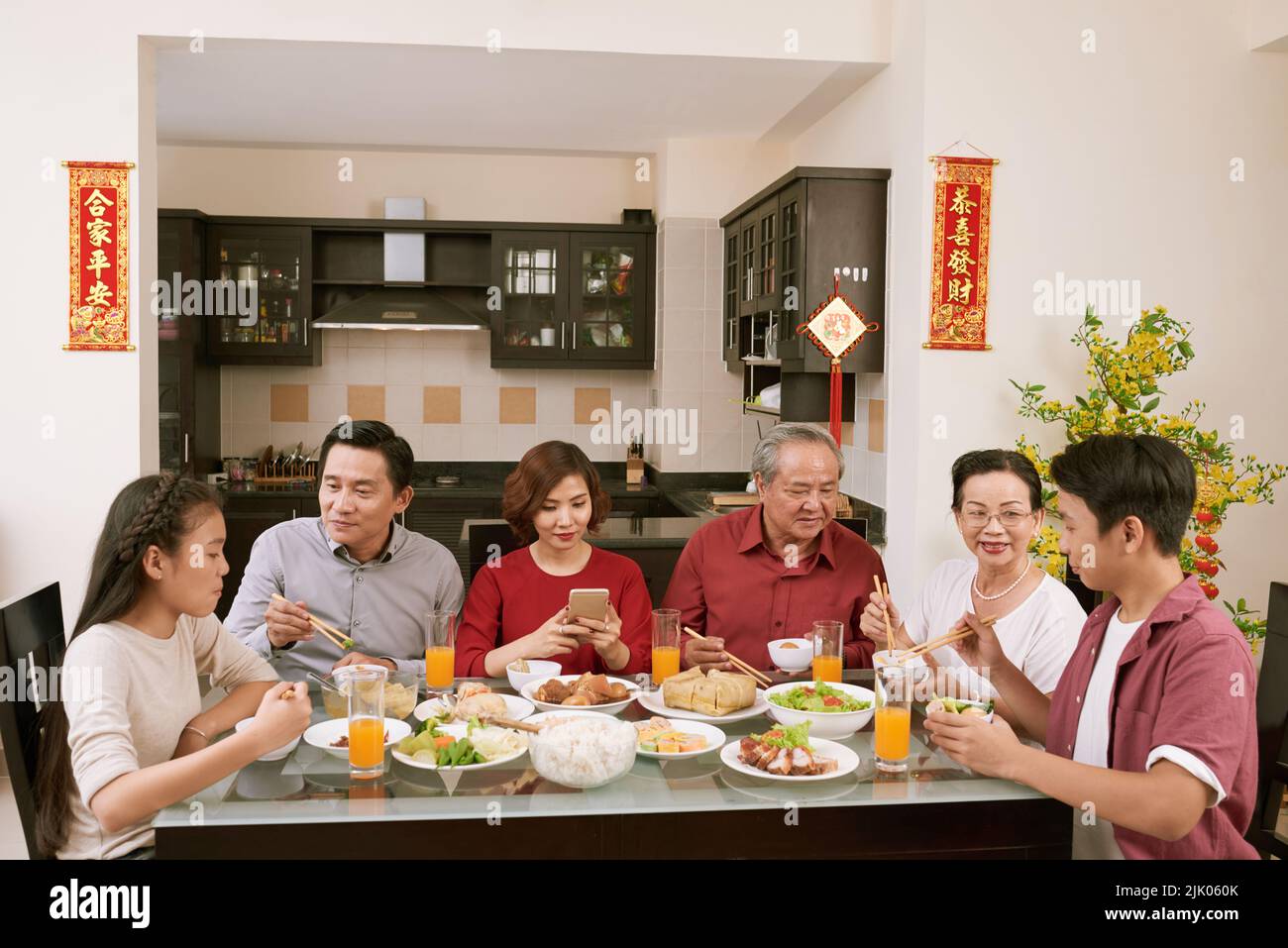 Grande famiglia asiatica che si gode una grande cena per la celebrazione di Capodanno. Scorre desiderio di fortuna e ricchezza in background Foto Stock