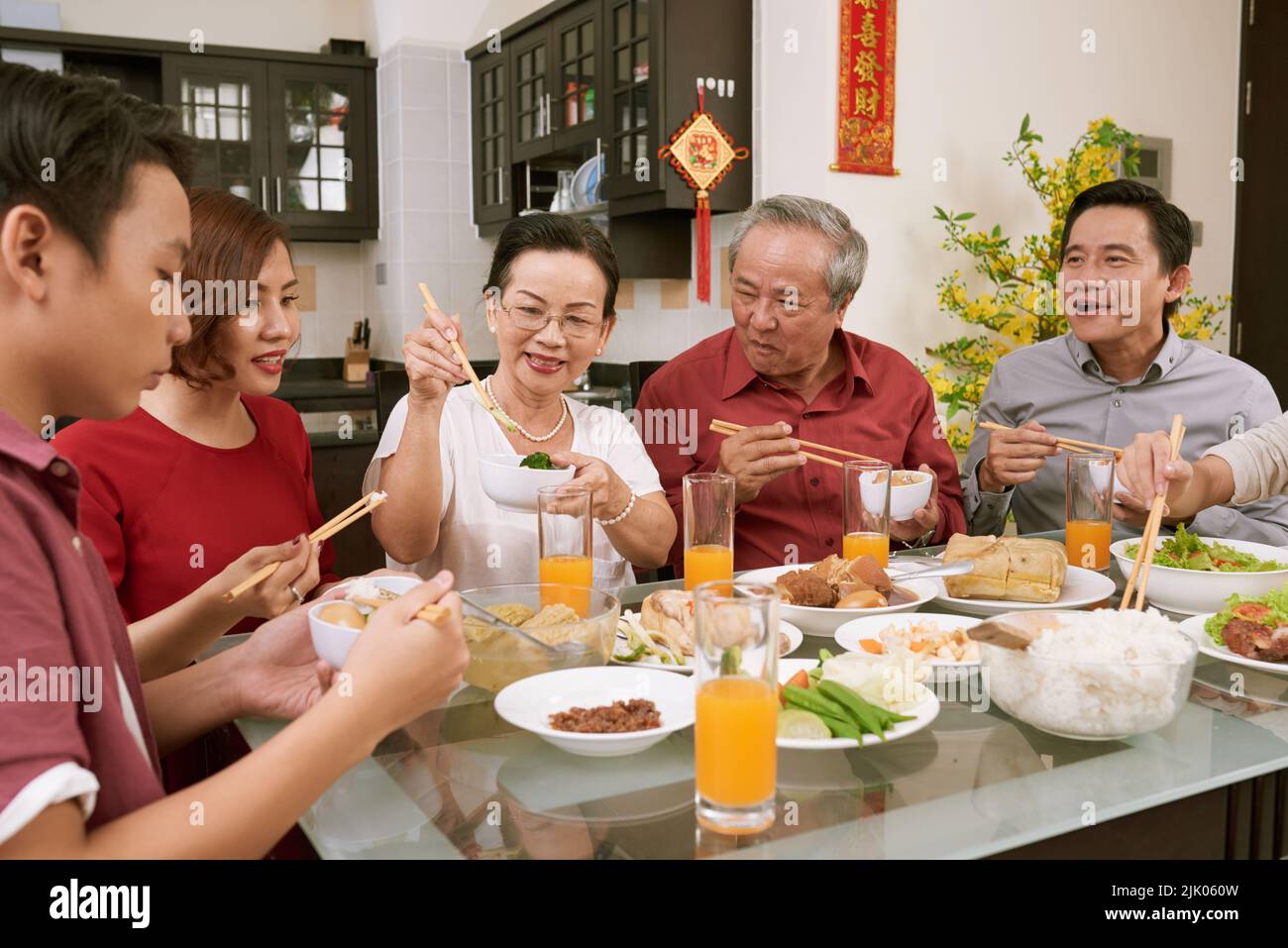 La famiglia mangia vari piatti tradizionali alla festa del Tet. Scorre desiderio di fortuna e ricchezza in background Foto Stock