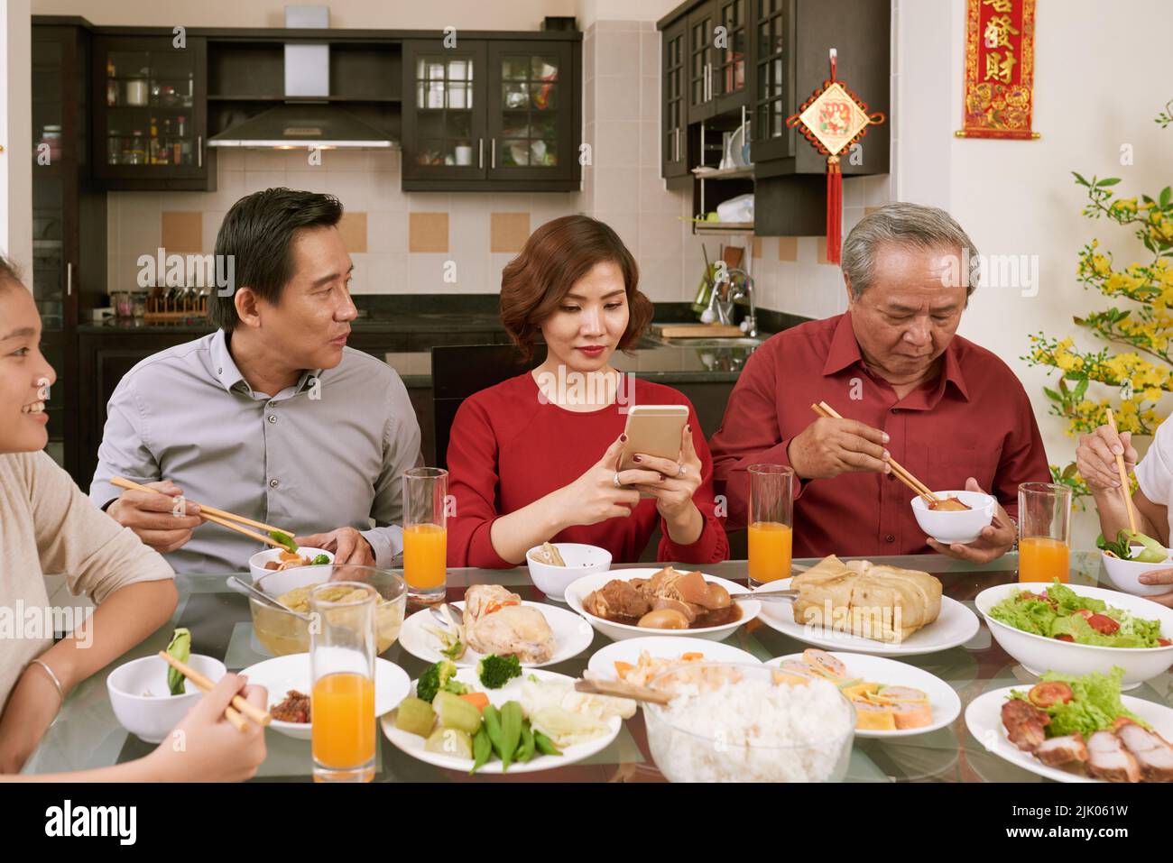 Donna asiatica graziosa che scatta le foto del cibo alla celebrazione di Capodanno cinese. Scorre desiderio di fortuna e ricchezza in background Foto Stock